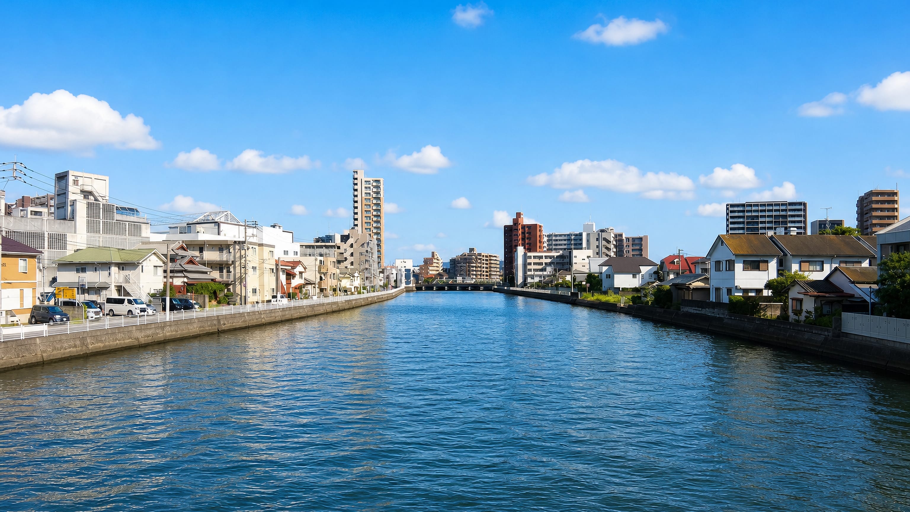 Houses and apartment blocks lining the Muromi River under a blue sky in Muromi, Fukuoka.