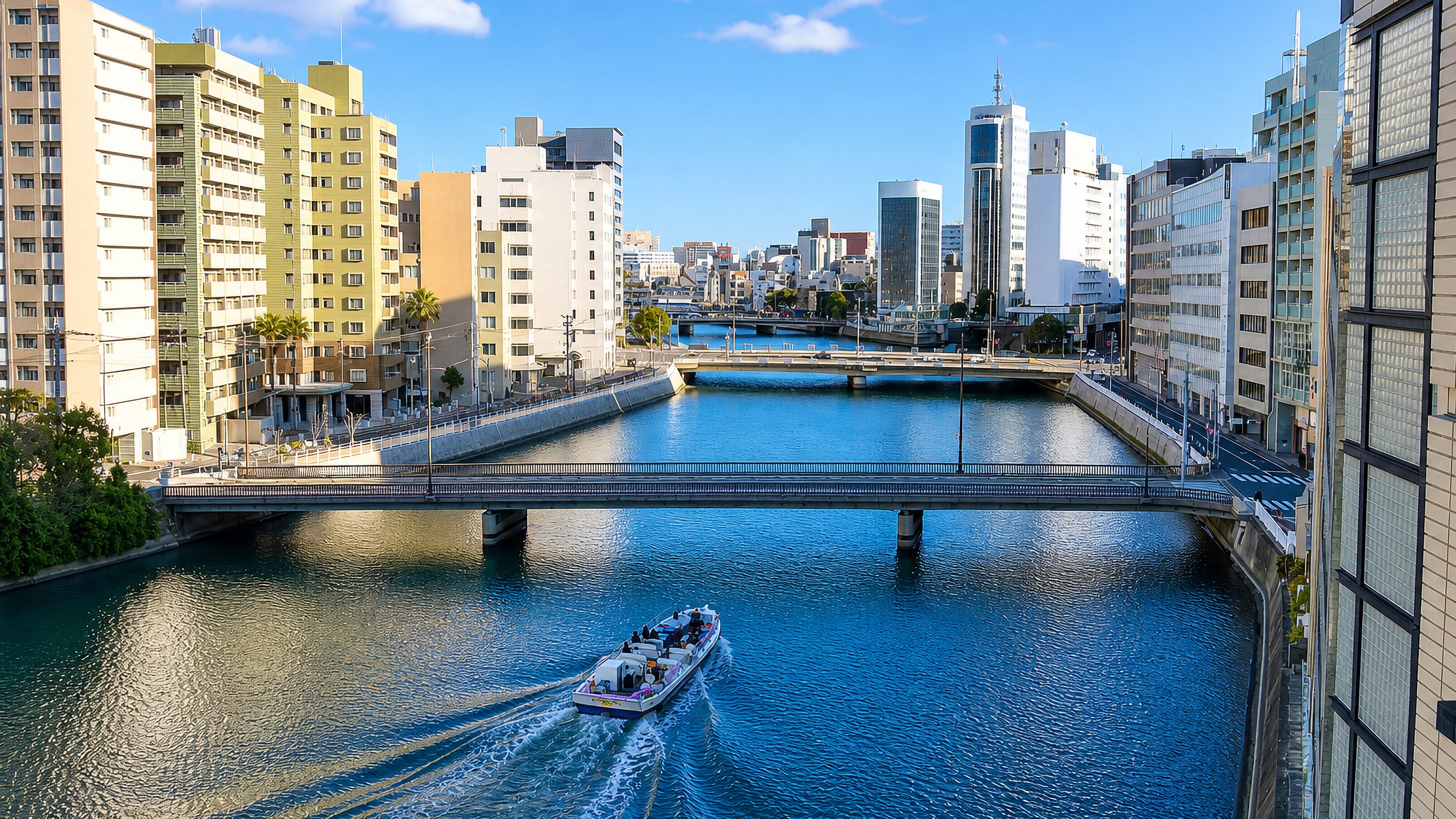 Canal-side towers and low bridges with a boat passing in Nakasu-nakashimamachi, Fukuoka.