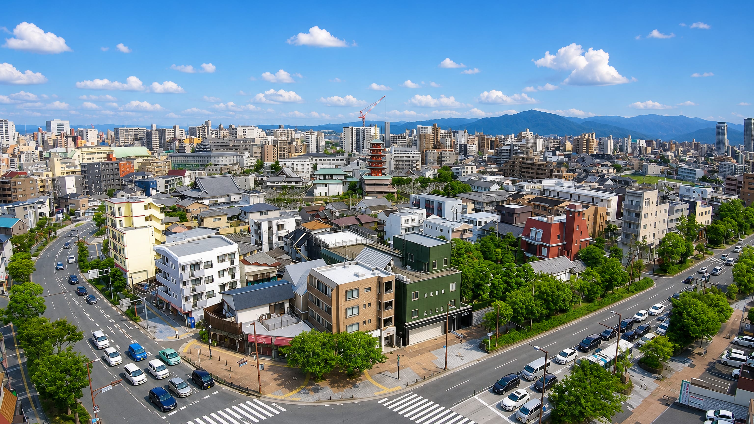 Wide daytime rooftop view over Tojinmachi in Fukuoka, low townhouses and a pagoda with mountains on the horizon.