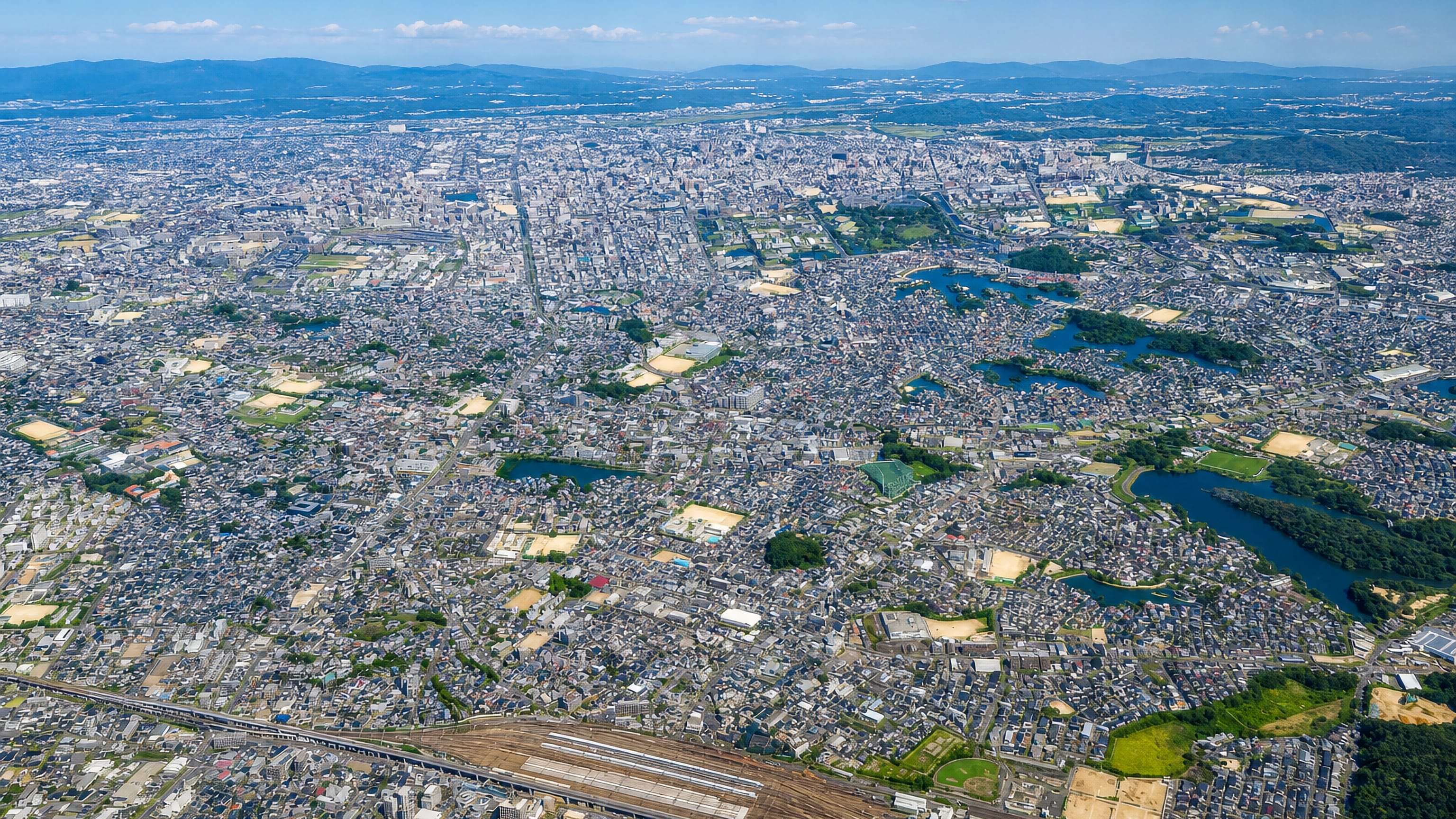 Aerial view over the dense residential sprawl and reservoir ponds of Kasuga in Fukuoka Prefecture.