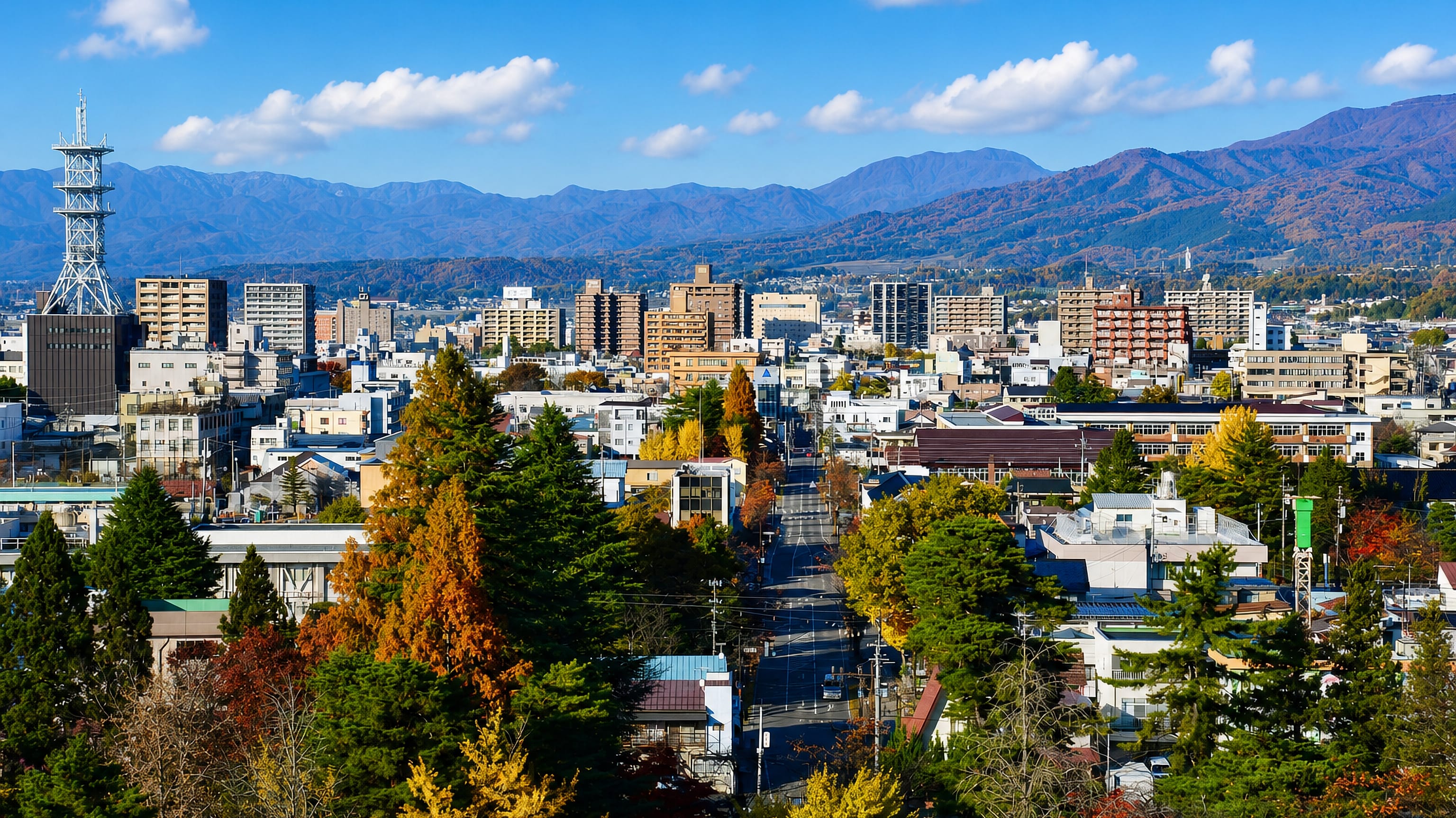 Autumn townscape of Aizu-Wakamatsu, mid-rise blocks and a broad avenue below the Fukushima mountains.