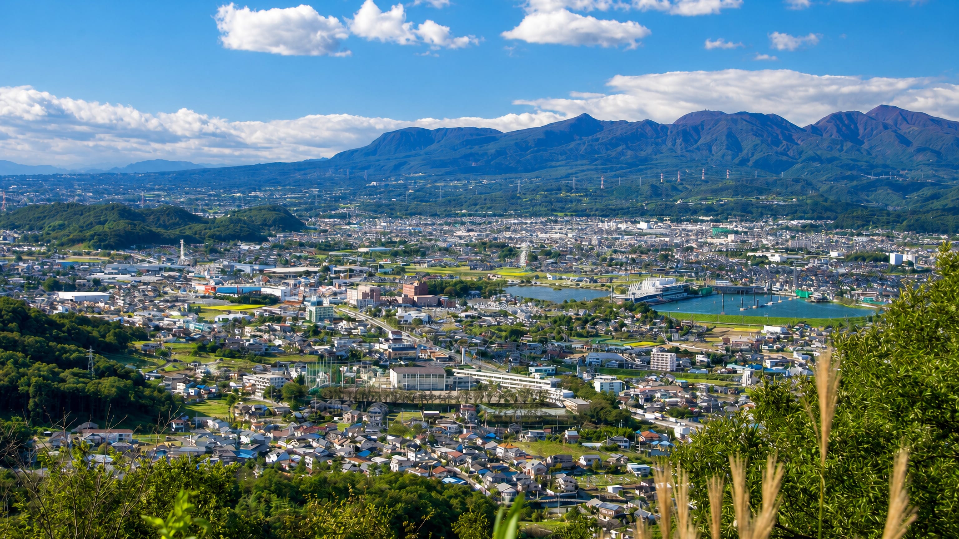 Kiryu filling its valley in Gunma, with mountain ridges behind and a Ferris wheel among the rooftops.