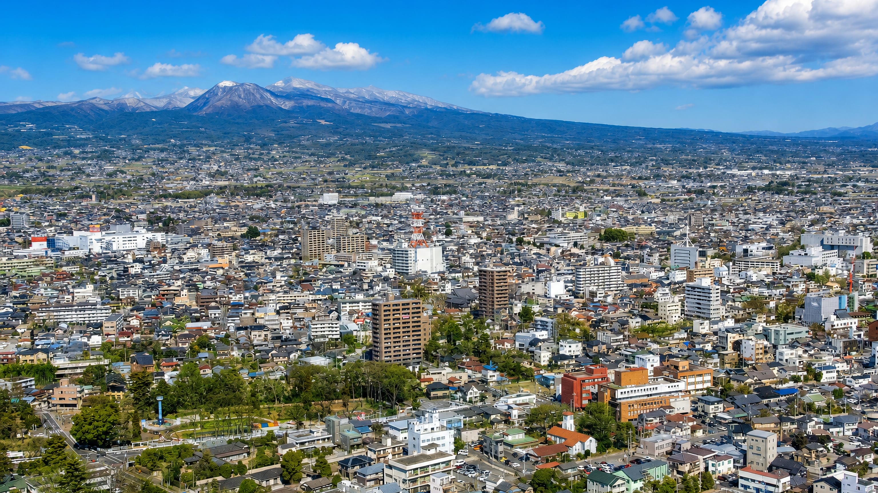 Maebashi, Japan, spread below the snow-capped peaks of the Gunma mountains under a clear sky.