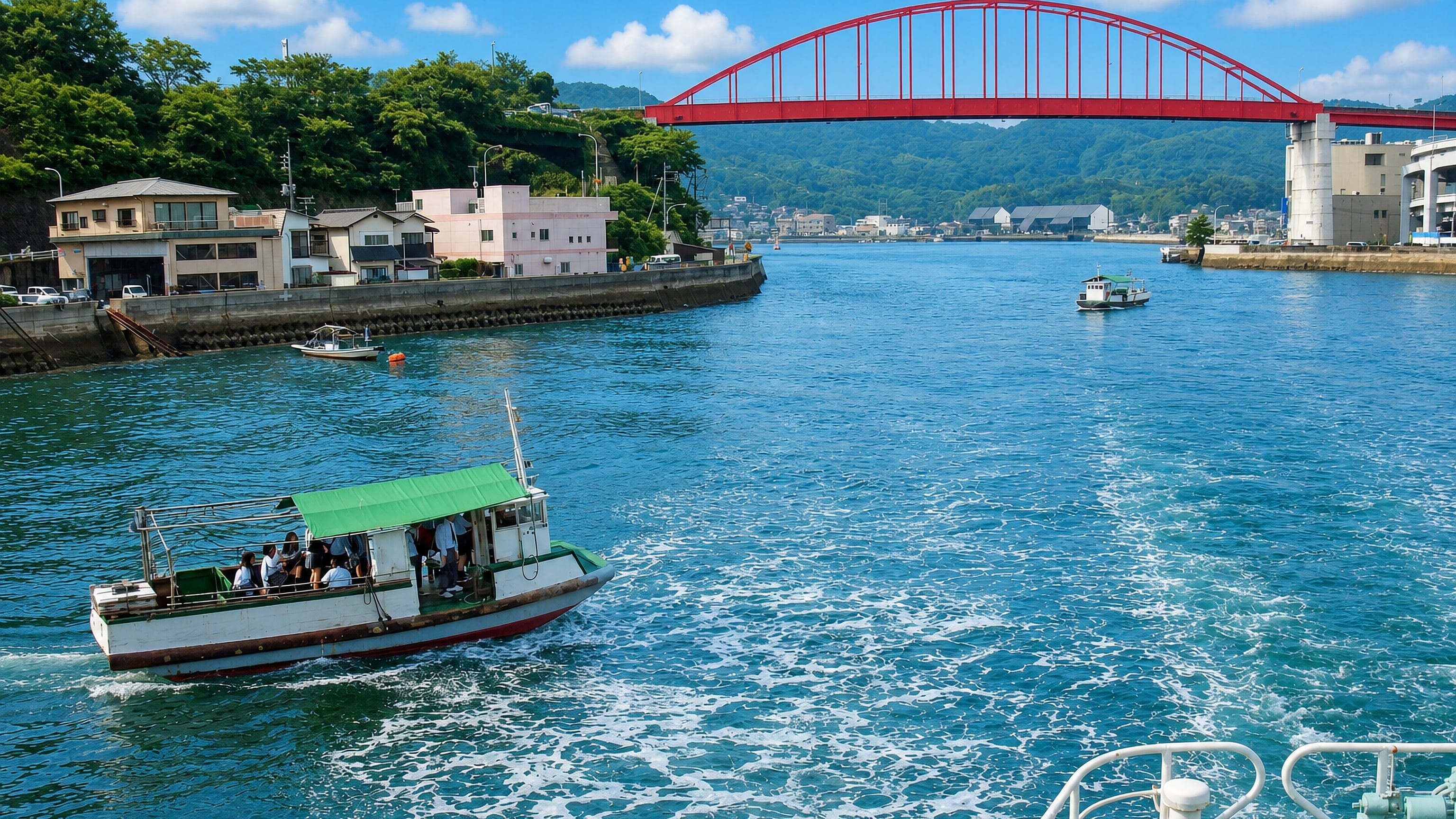 Red steel arch bridge over the Ondo Strait with small ferries passing at Kure, Hiroshima Prefecture