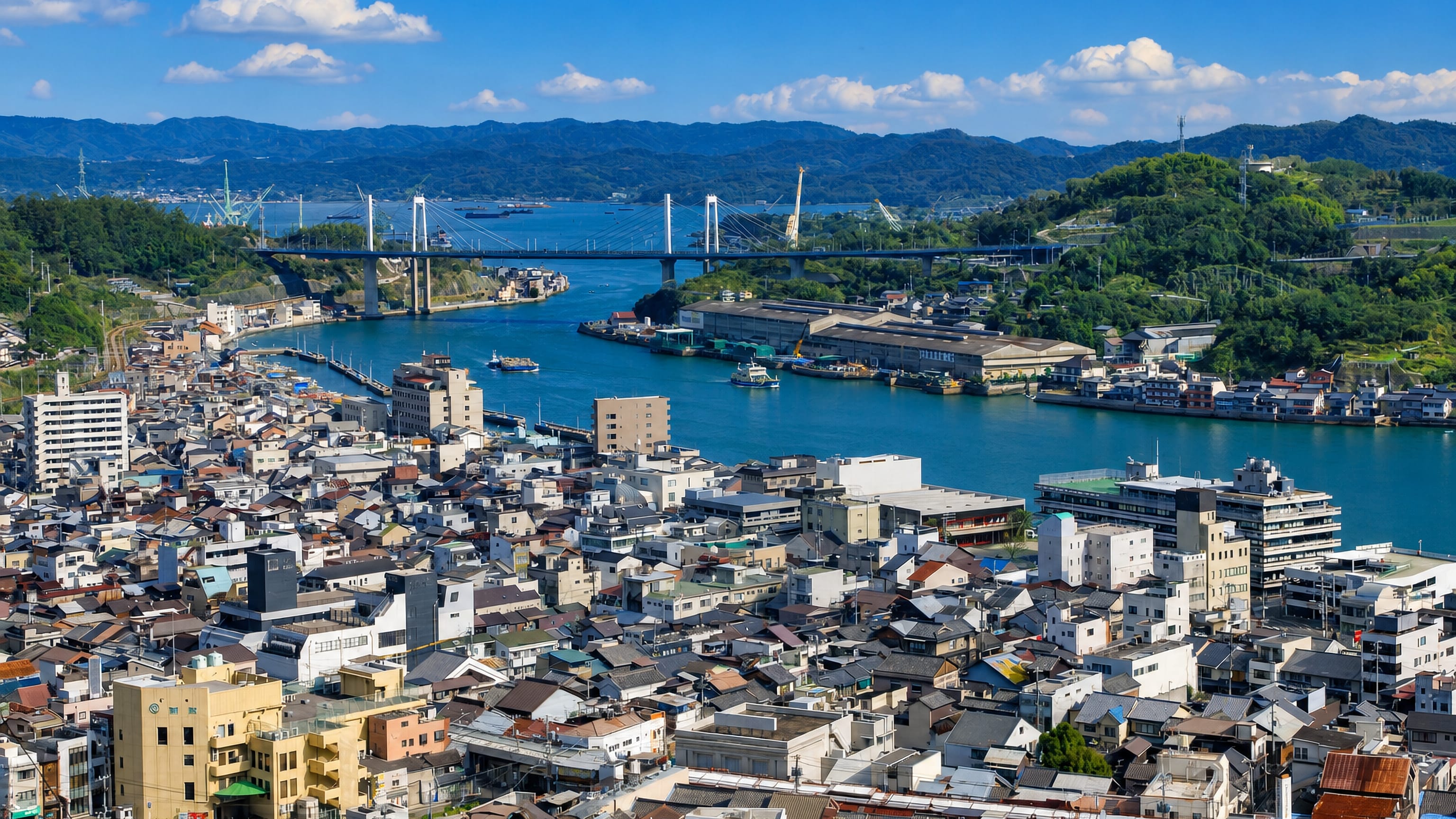 Onomichi, Japan, seen from the hillside across its dense townscape to the channel and the Onomichi Ohashi bridge.