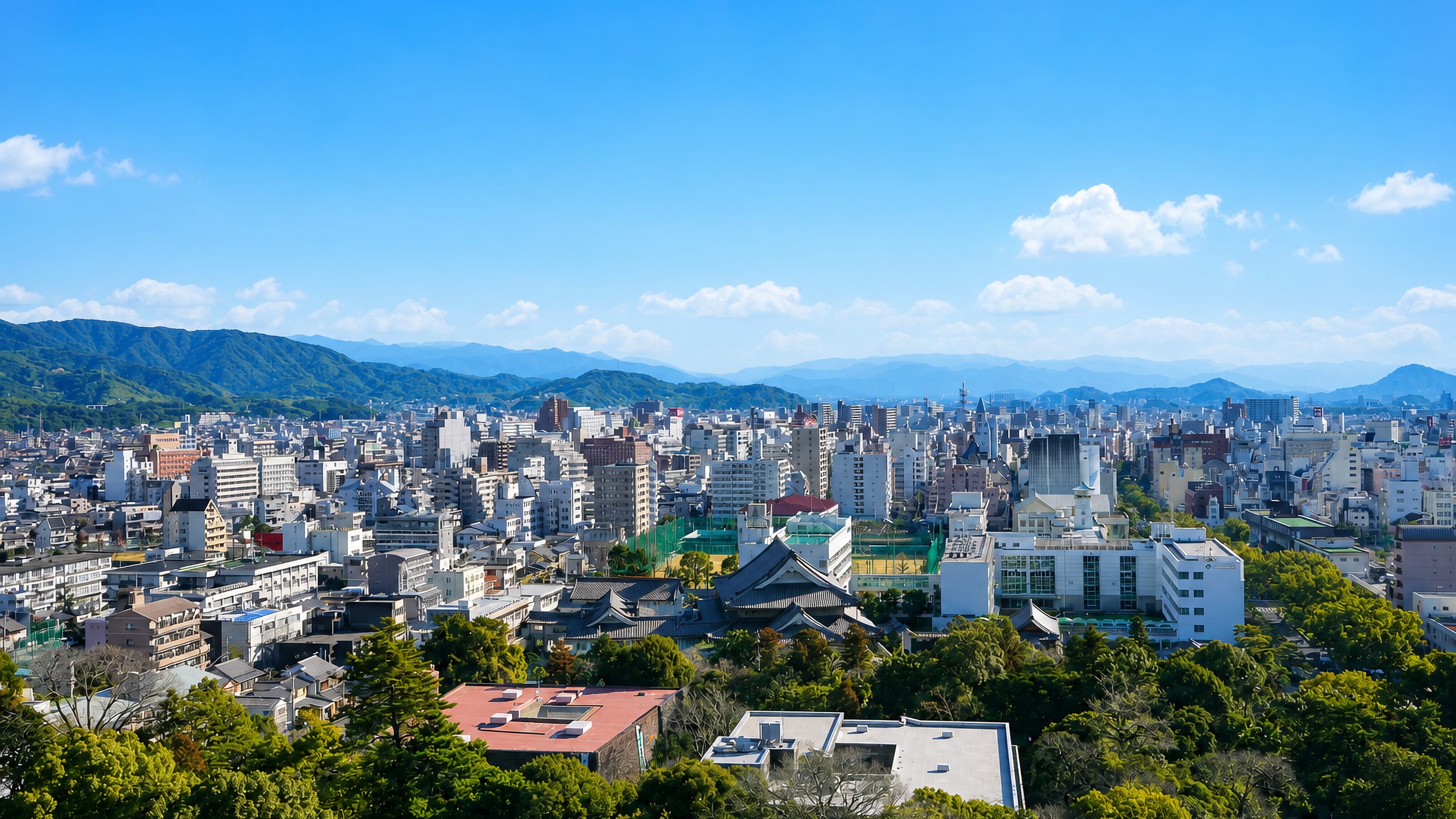 Low-rise Kochi city with traditional tiled roofs ringed by green mountains in Kochi Prefecture, Japan.