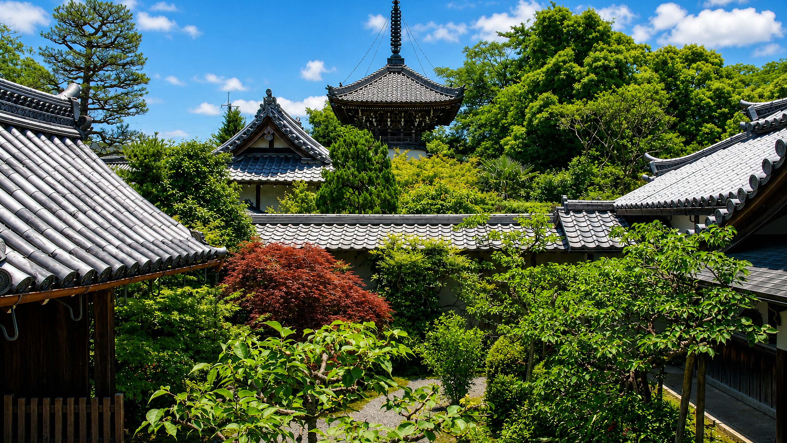 Tiled temple roofs and a pagoda above a green garden courtyard in Kameoka, Kyoto Prefecture.