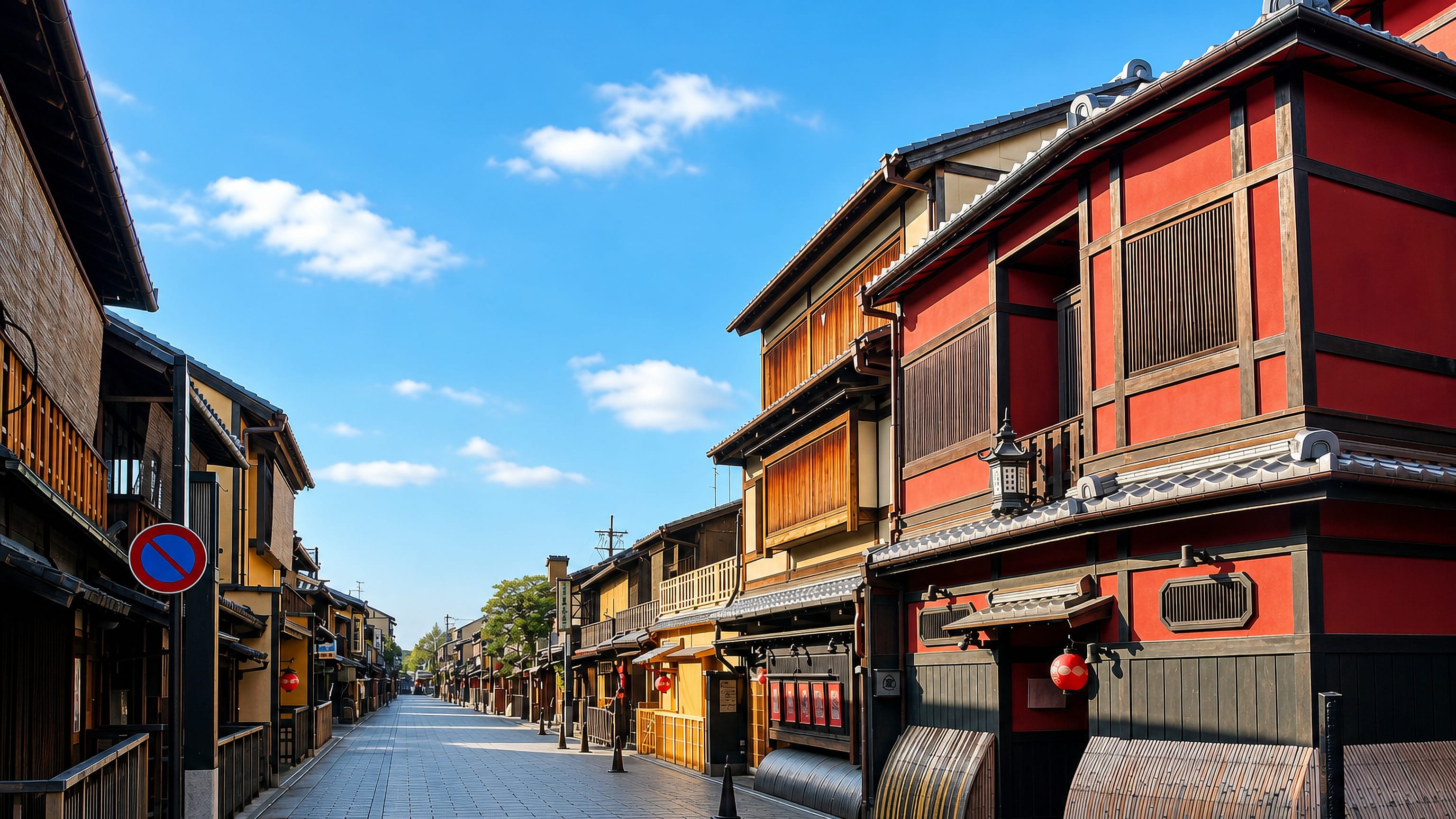 Wooden machiya teahouses with red lanterns and bamboo screens line a stone-paved street in Gion, Kyoto.