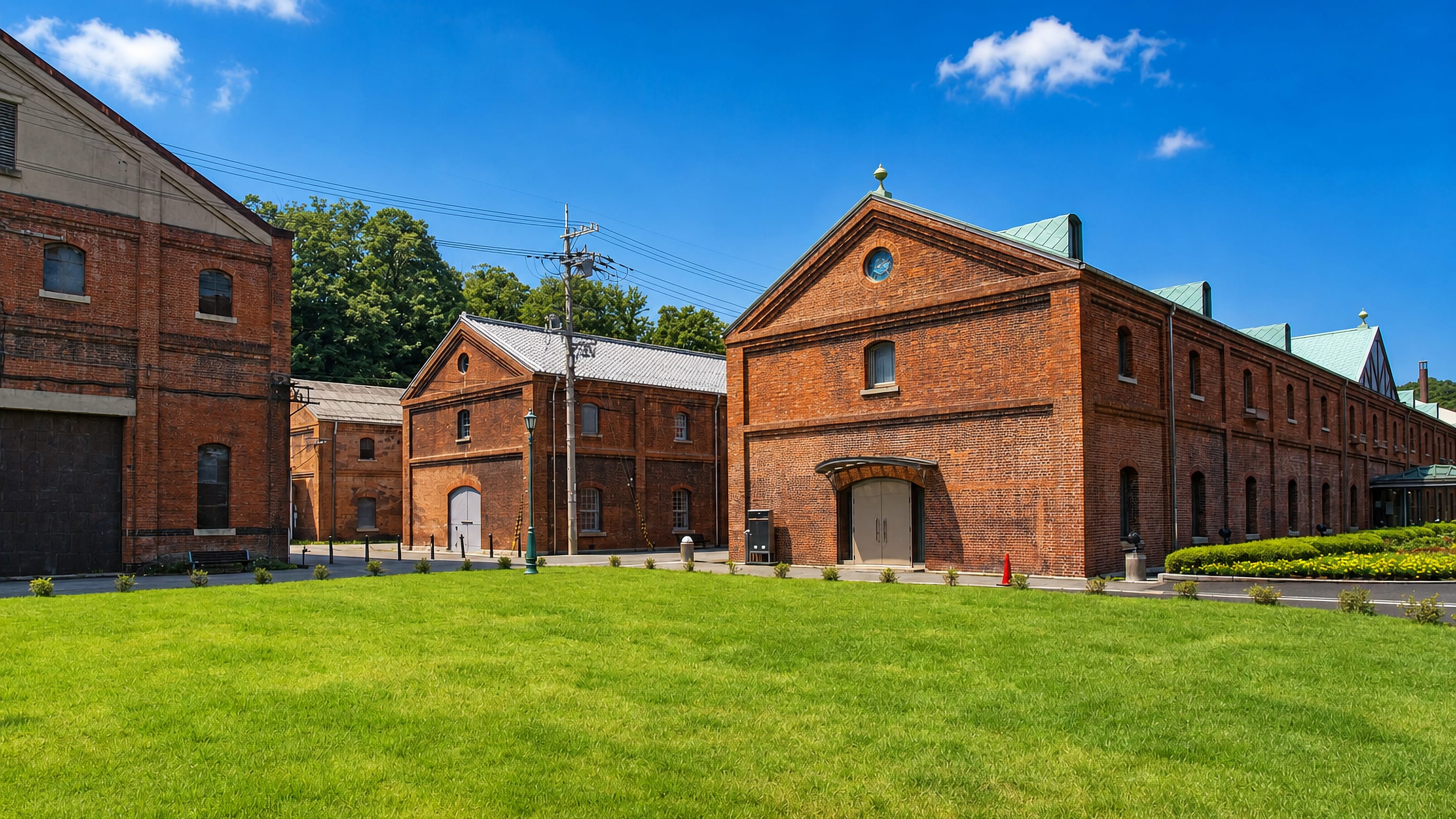 The red brick warehouses of Maizuru, Japan, standing along a lawn under a clear summer sky.