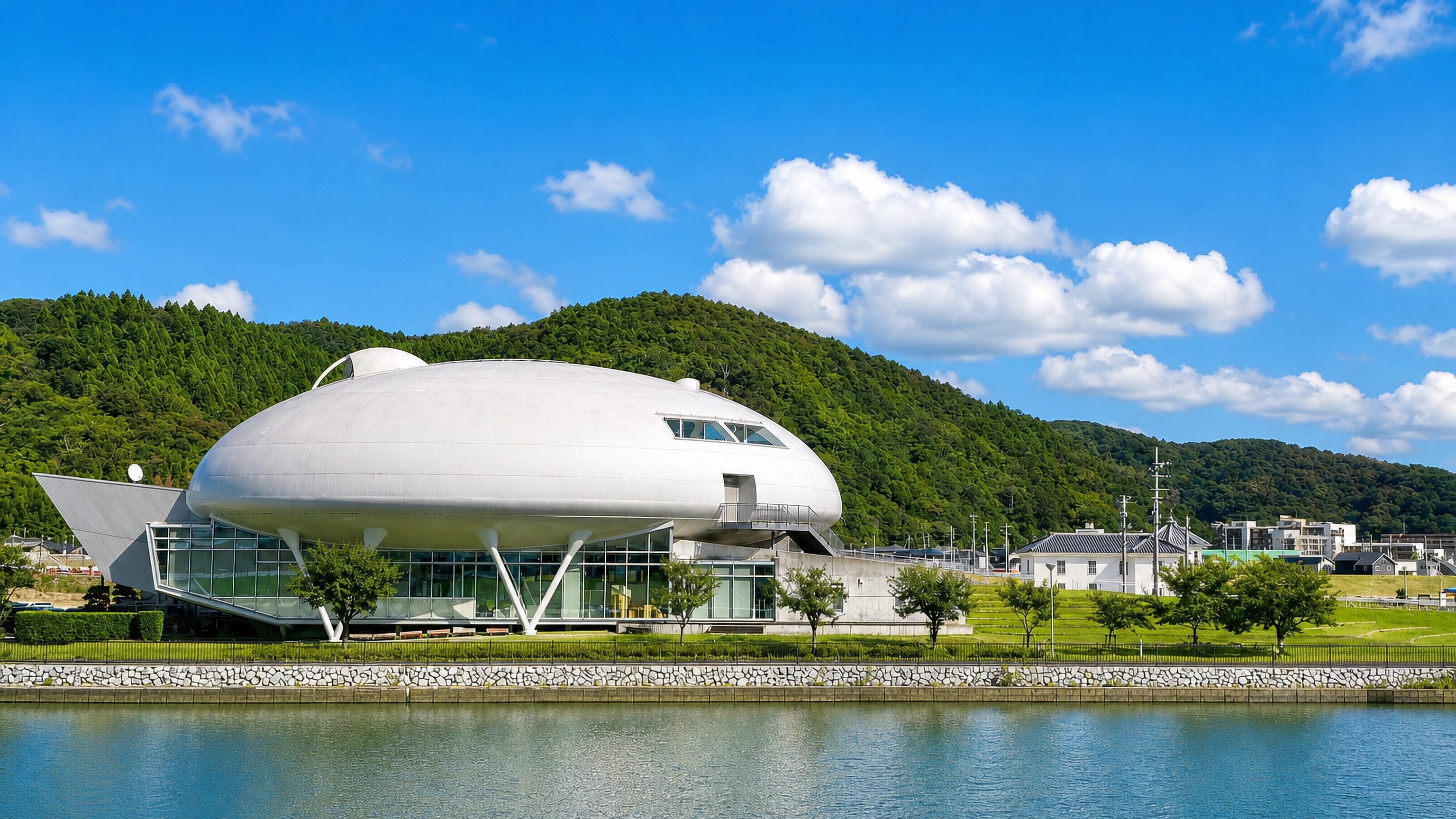 White spaceship-shaped riverside museum backed by wooded hills at Ishinomaki, Miyagi.