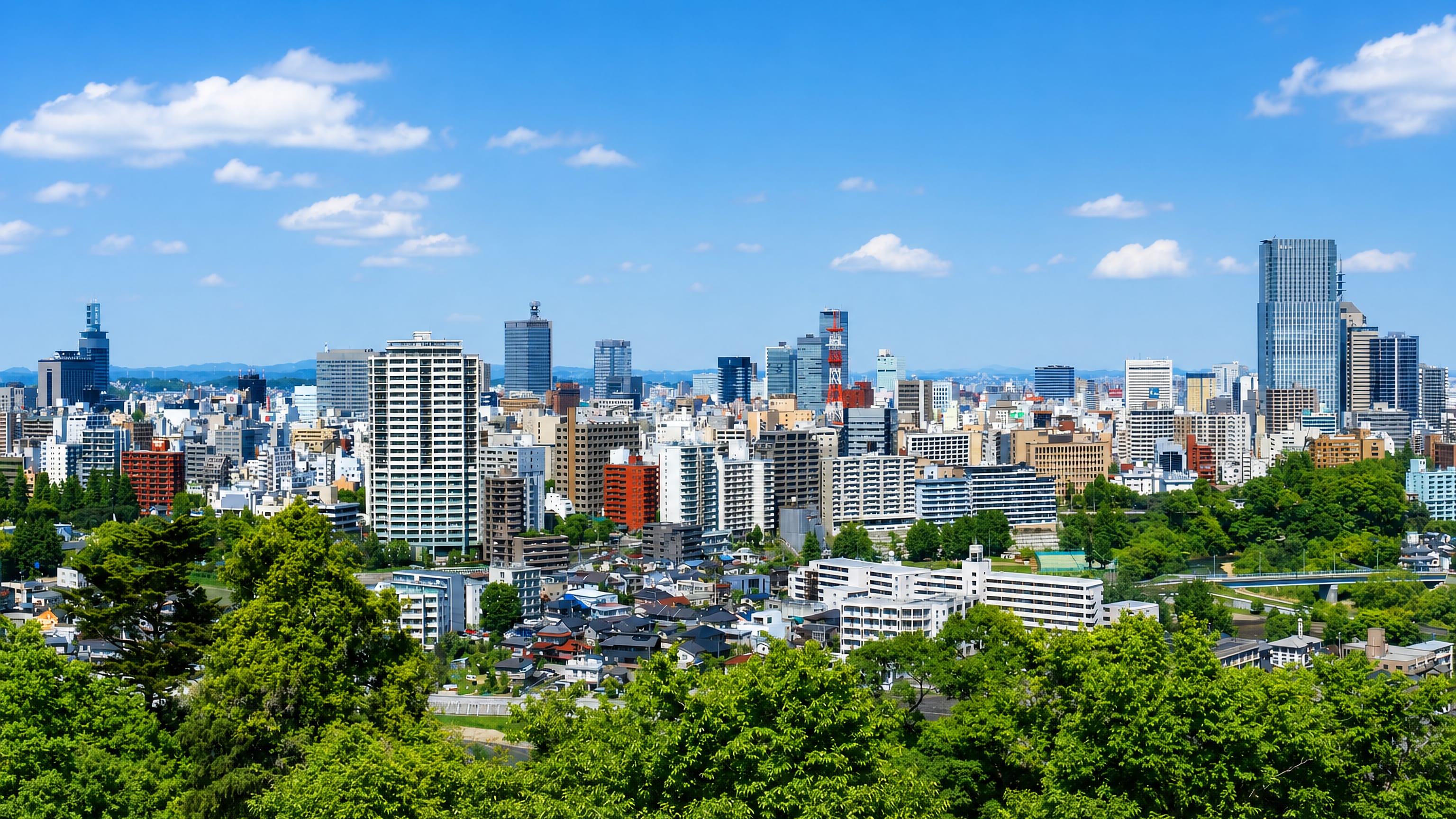 Sendai skyline in Miyagi, high-rise towers rising beyond the green trees of the surrounding hills.