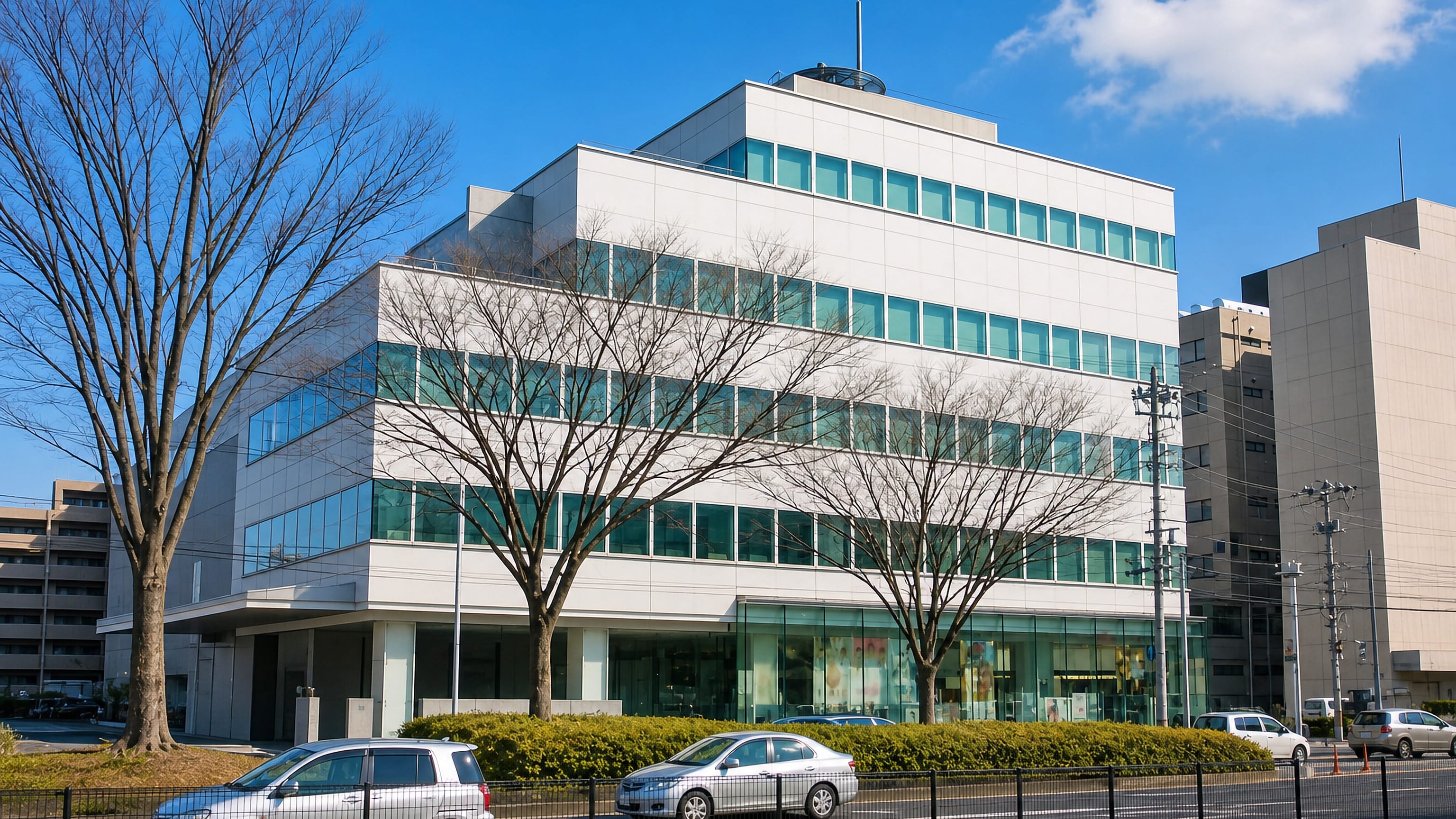A white mid-rise office block on a tree-lined avenue in Kamisugi, central Sendai