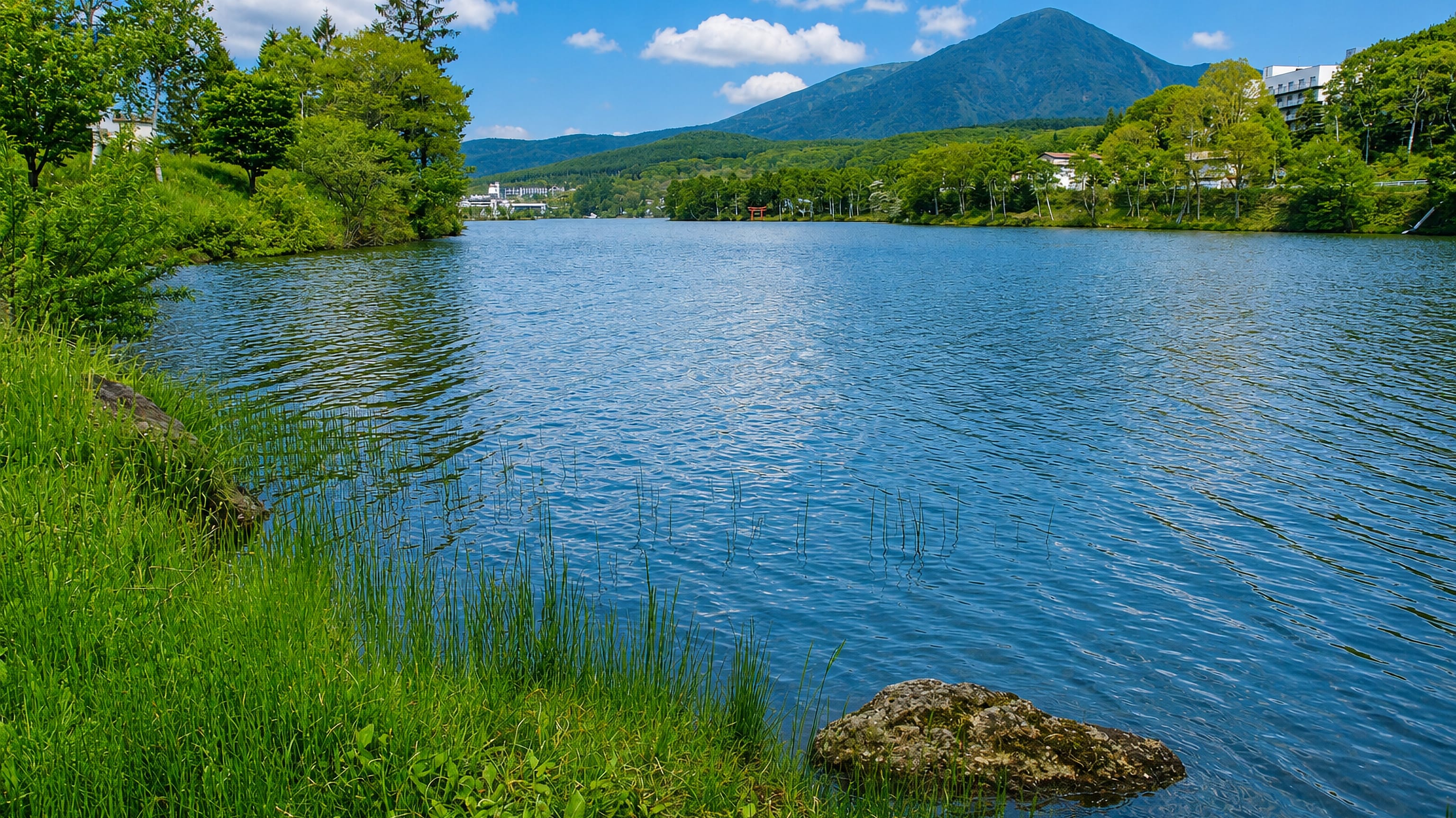 Lake Tateshina at Chino, Japan, with the cone of Mount Tateshina rising beyond wooded shores.