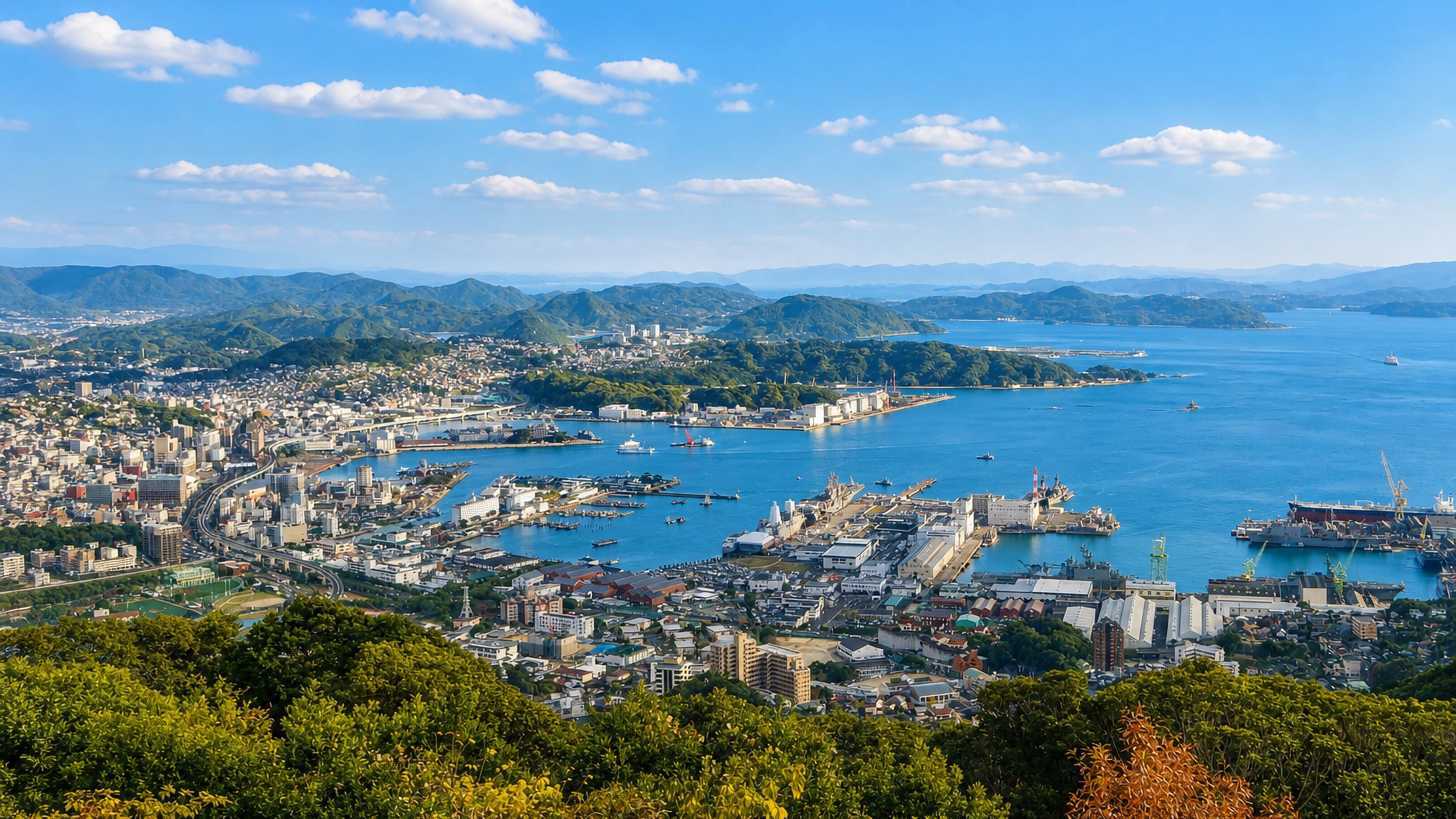 Sasebo's harbour, naval base and shipyard cranes seen from the wooded hills above the city, Nagasaki Prefecture