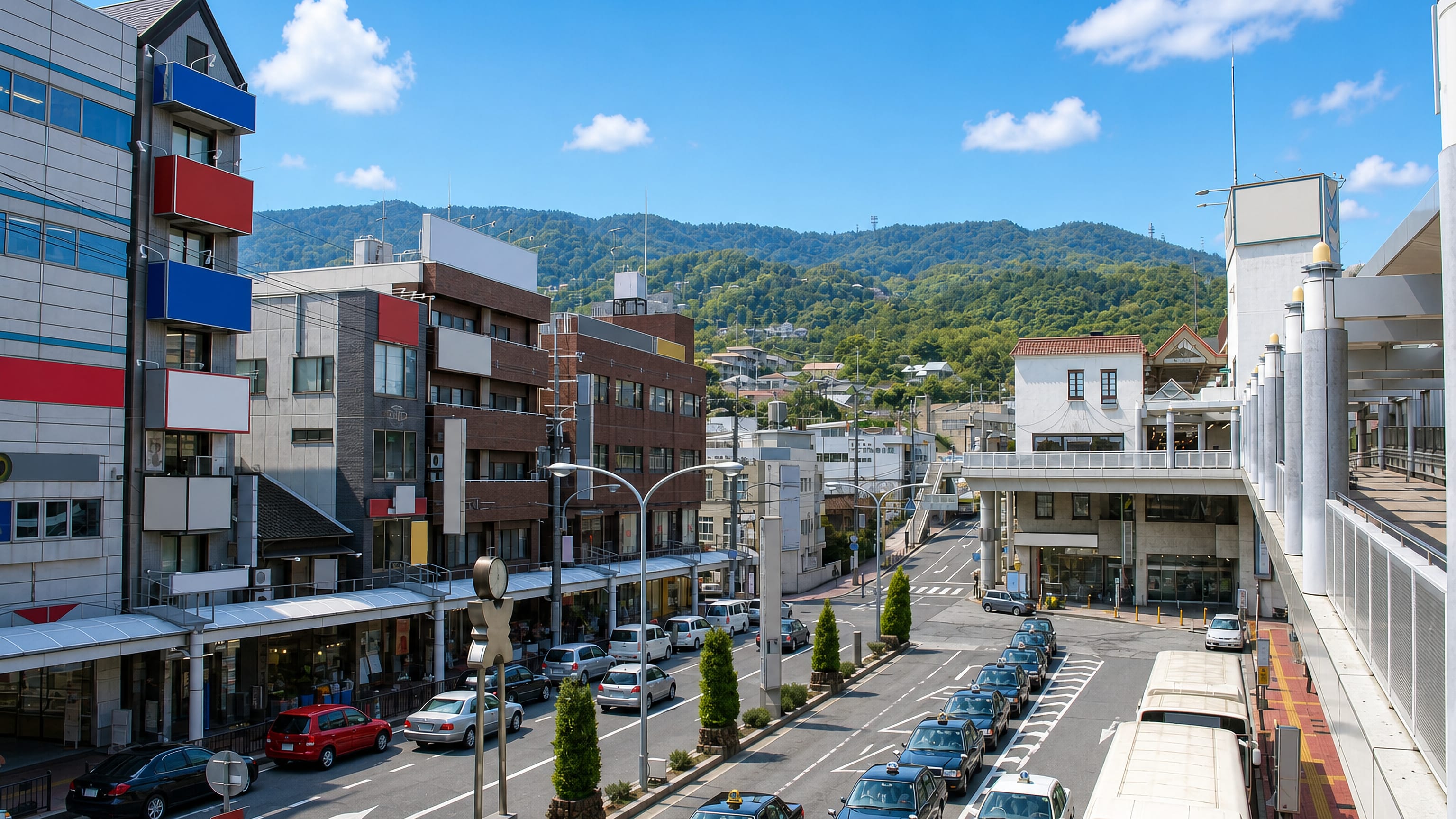 Station-front street in Ikoma, Nara Prefecture, with taxi rank, pedestrian deck and wooded Mount Ikoma behind