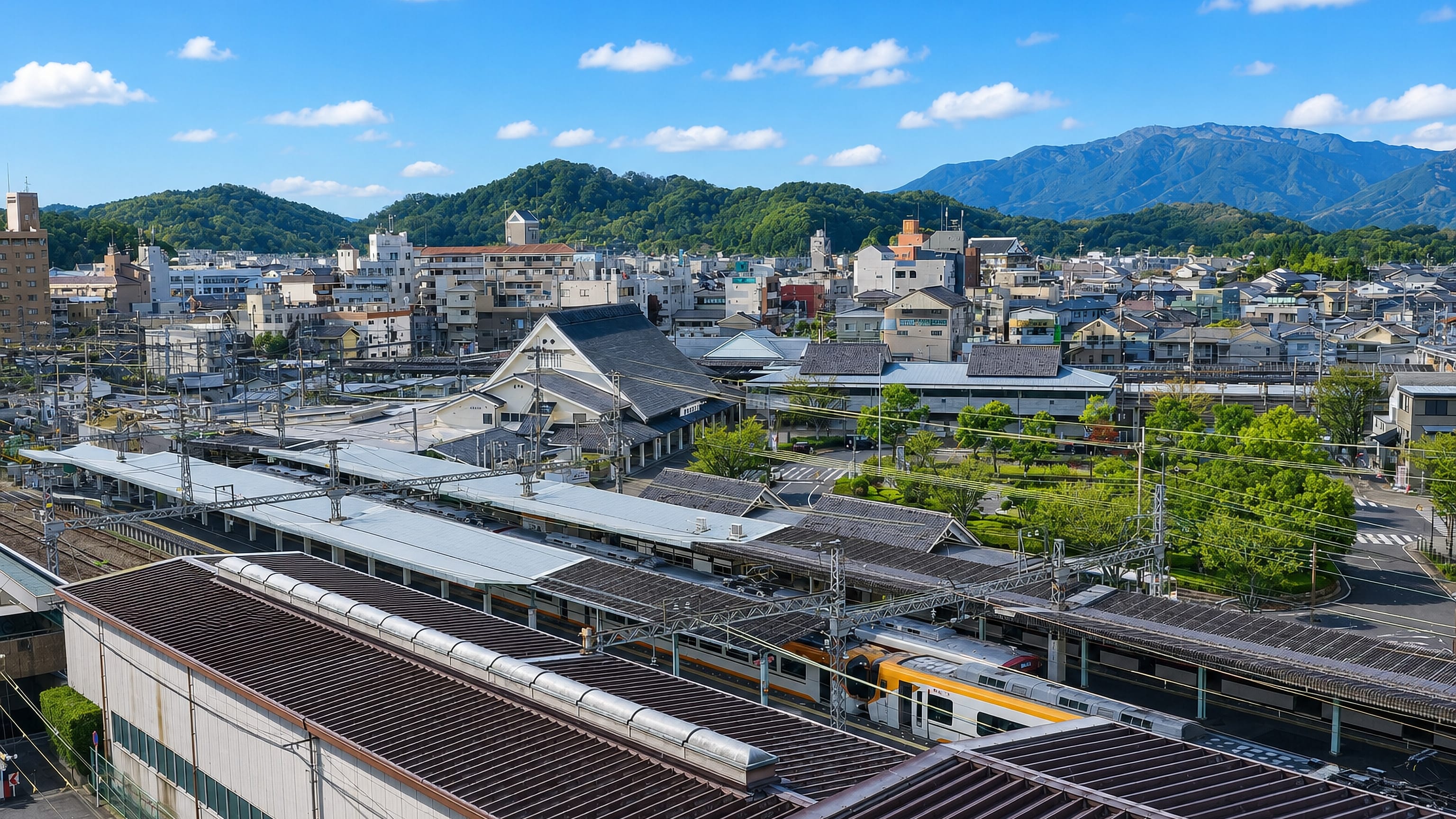 Elevated view over Kashihara, Nara, with Kintetsu trains at its temple-style station and mountains beyond