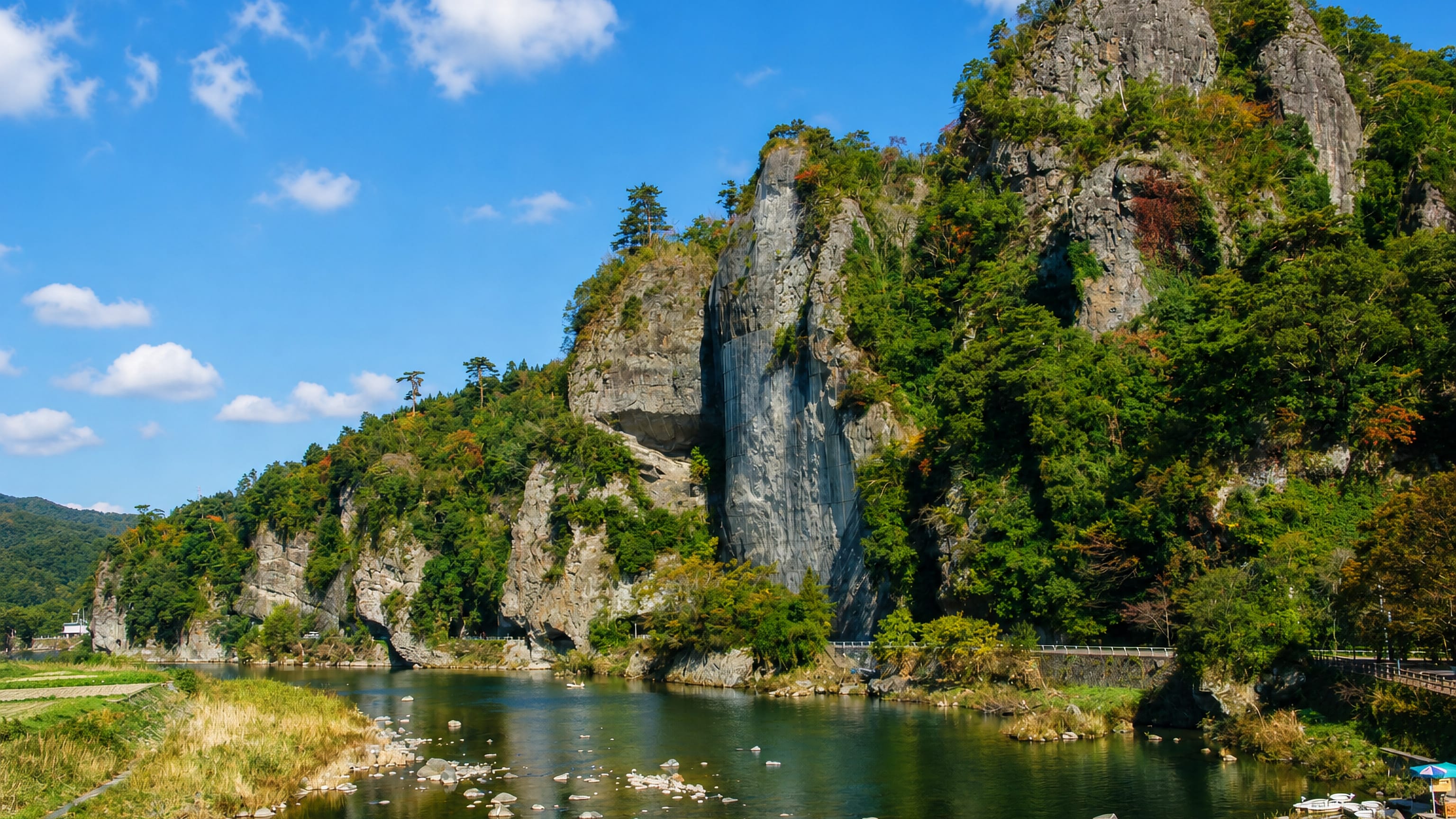 Limestone cliffs of the Yabakei gorge rising above the Yamakuni River at Nakatsu, Oita, under a blue sky
