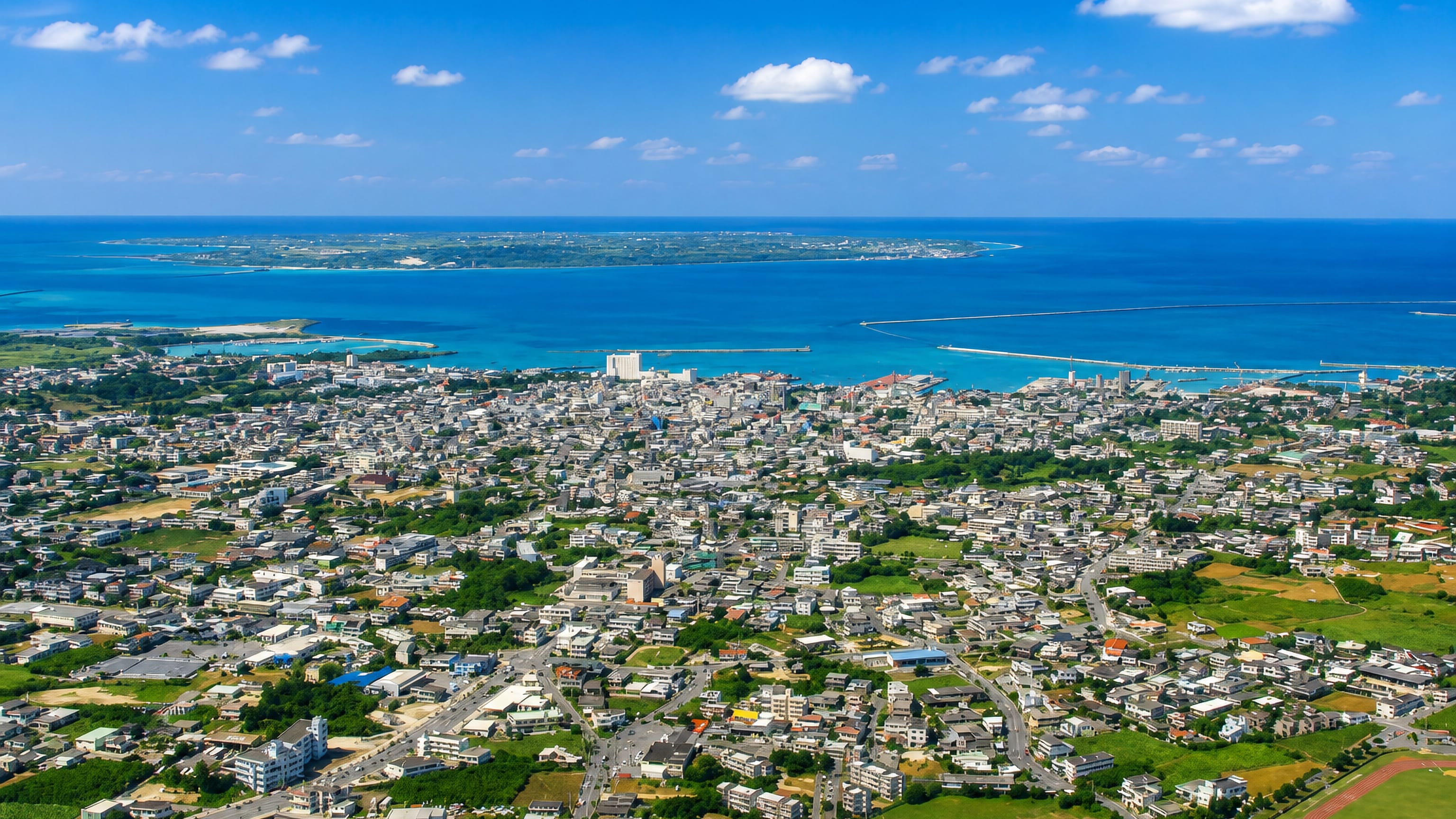 Hirara's low-rise townscape and harbour ringed by turquoise reef water on Miyakojima, Okinawa.
