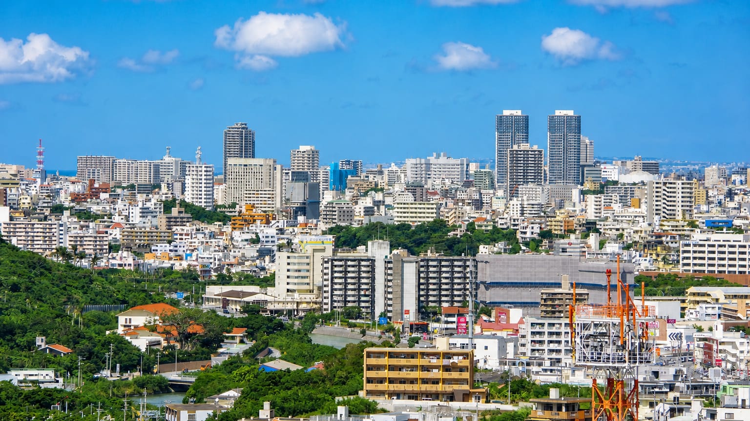 Naha cityscape in Okinawa, with dense mid-rise buildings and distant towers stretching toward the sea.