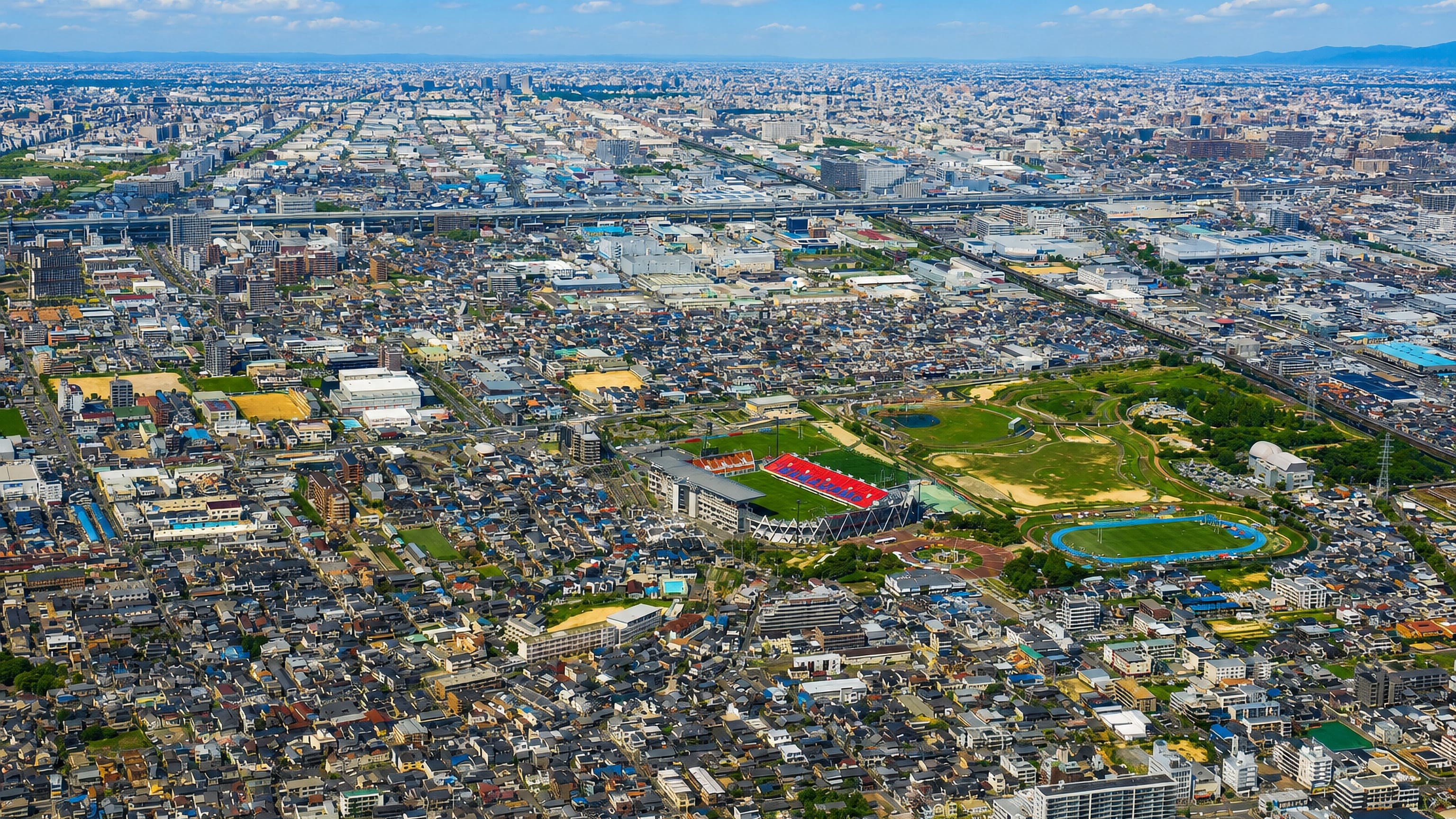 Aerial view of Higashiosaka spreading across the Osaka plain around Hanazono rugby stadium and its park