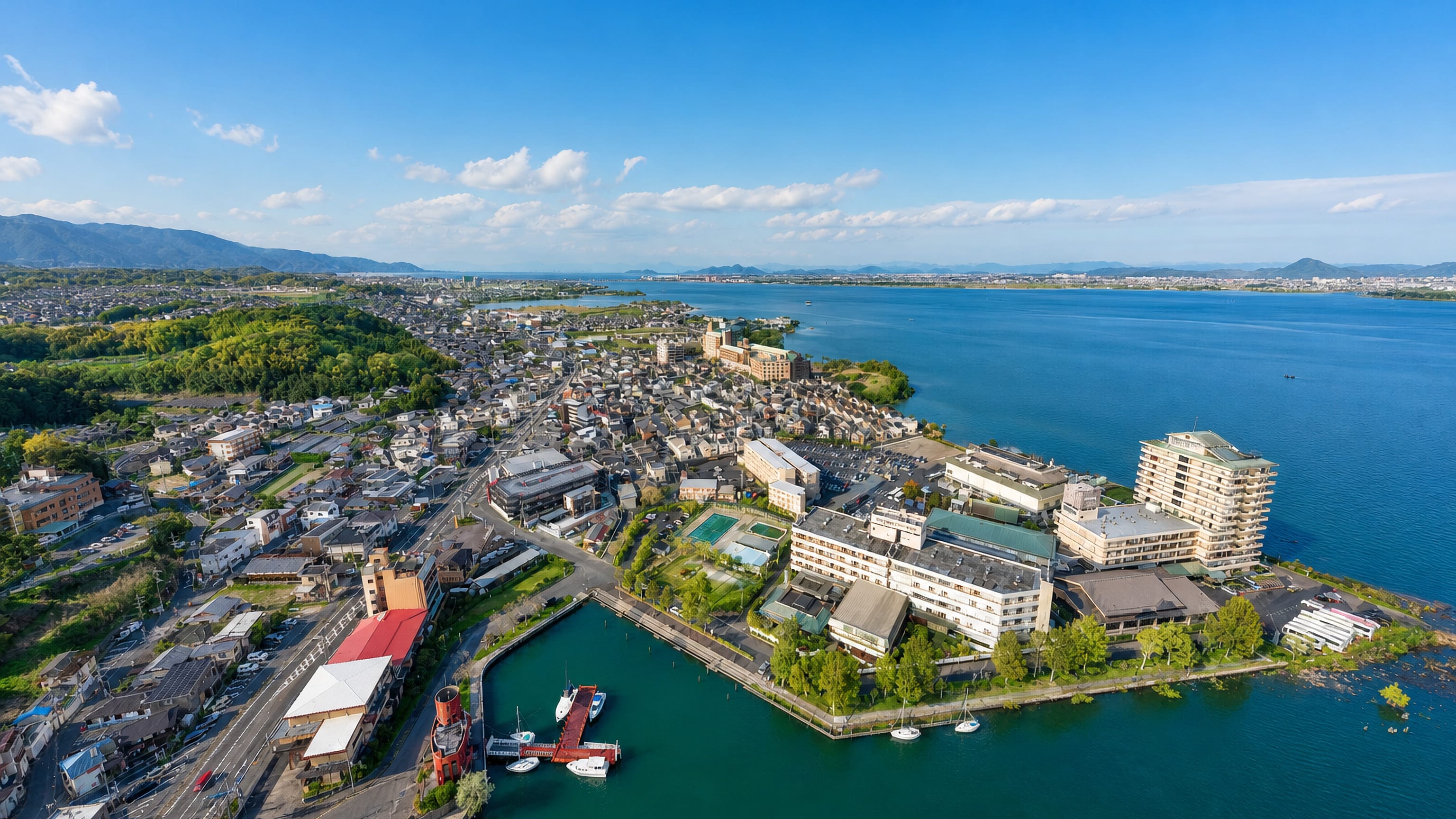 Aerial view of Nagahama, Japan, its lakeside hotels and marina meeting the blue water of Lake Biwa.