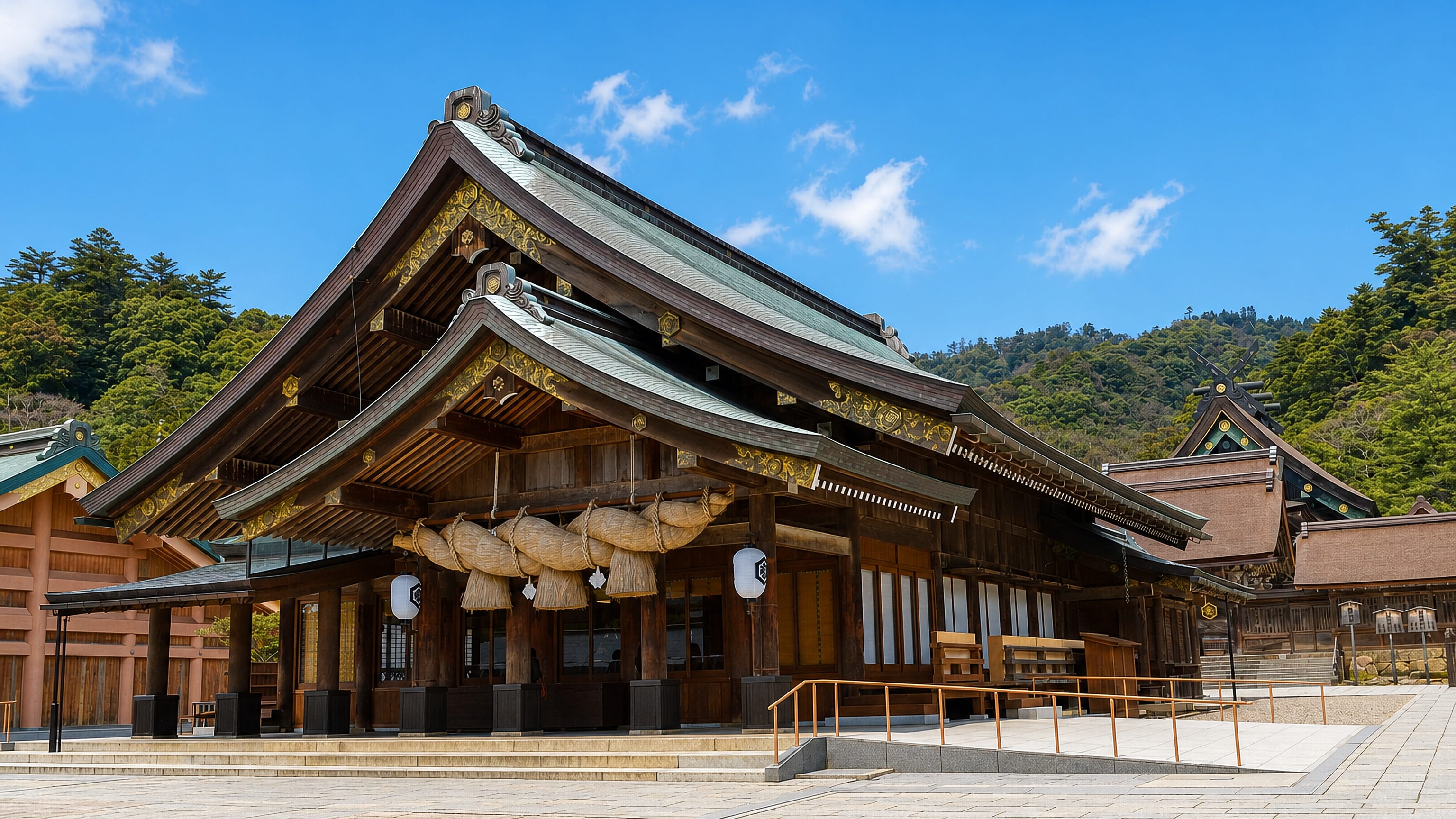 Izumo Taisha shrine hall with its giant shimenawa rope and sweeping roof beneath wooded hills in Izumo, Japan.
