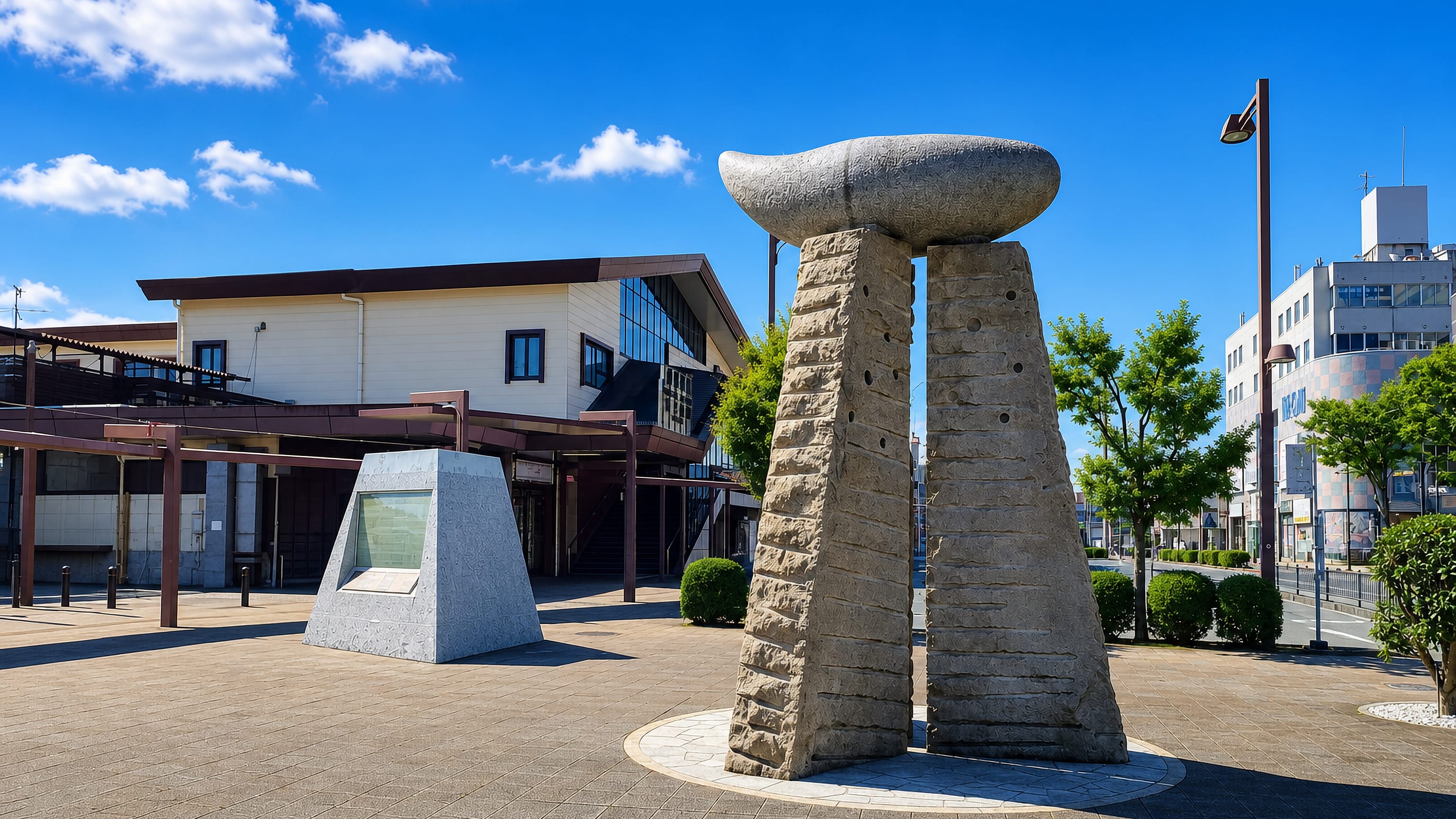 Stone monument on the paved plaza outside Gotemba station in Shizuoka, with low town buildings behind