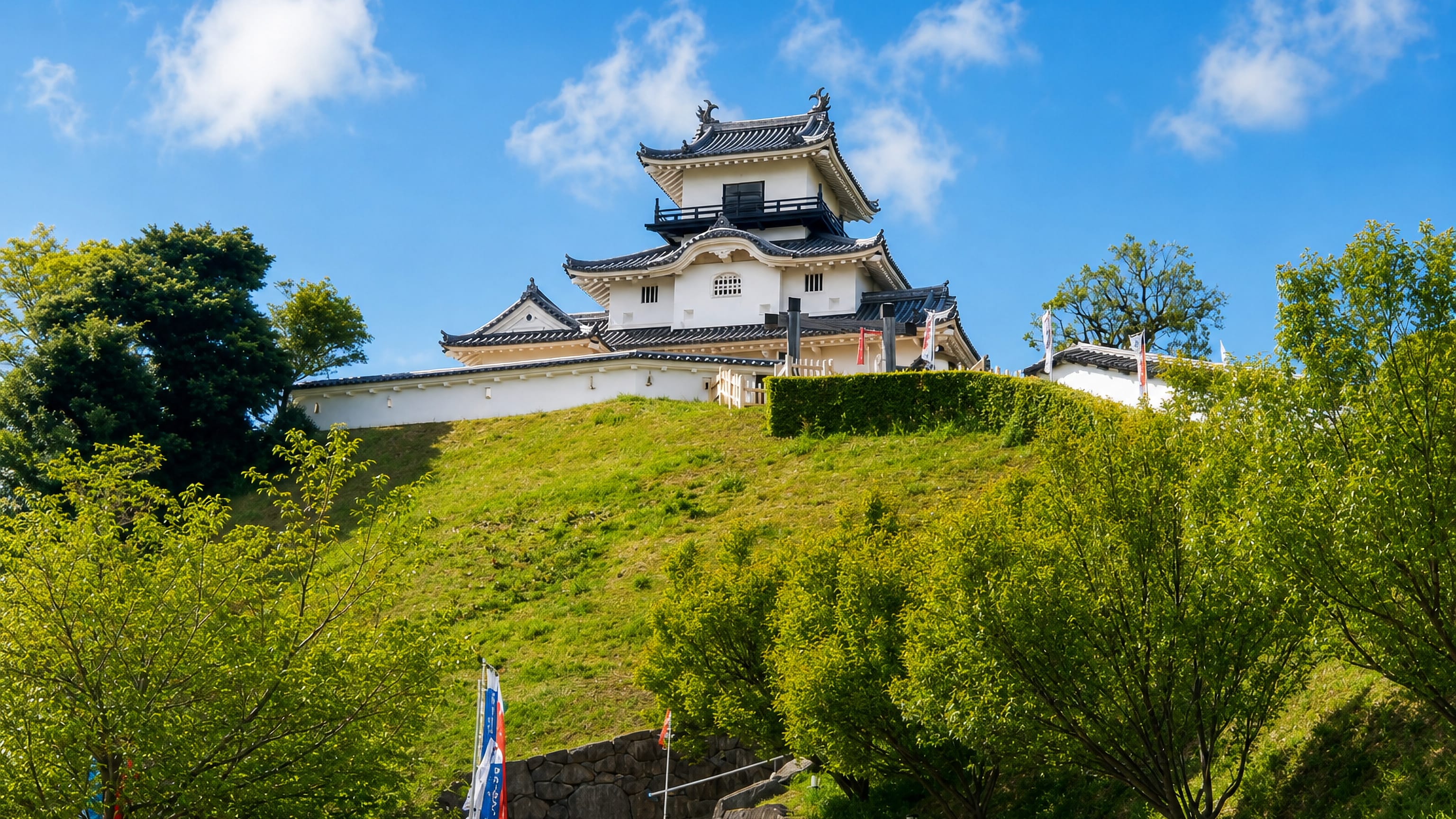 Kakegawa Castle's white keep on its green hilltop above a stone stairway in Shizuoka, Japan.