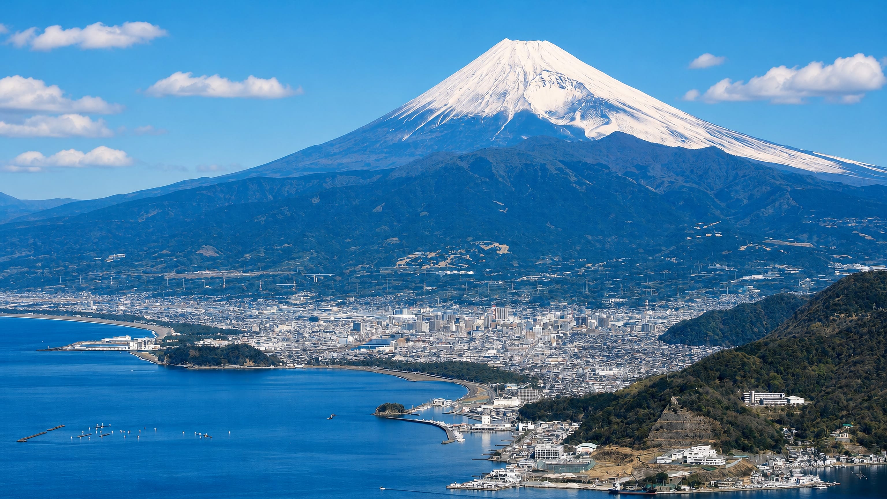 Numazu, Japan, on Suruga Bay with snow-capped Mount Fuji rising behind the city.