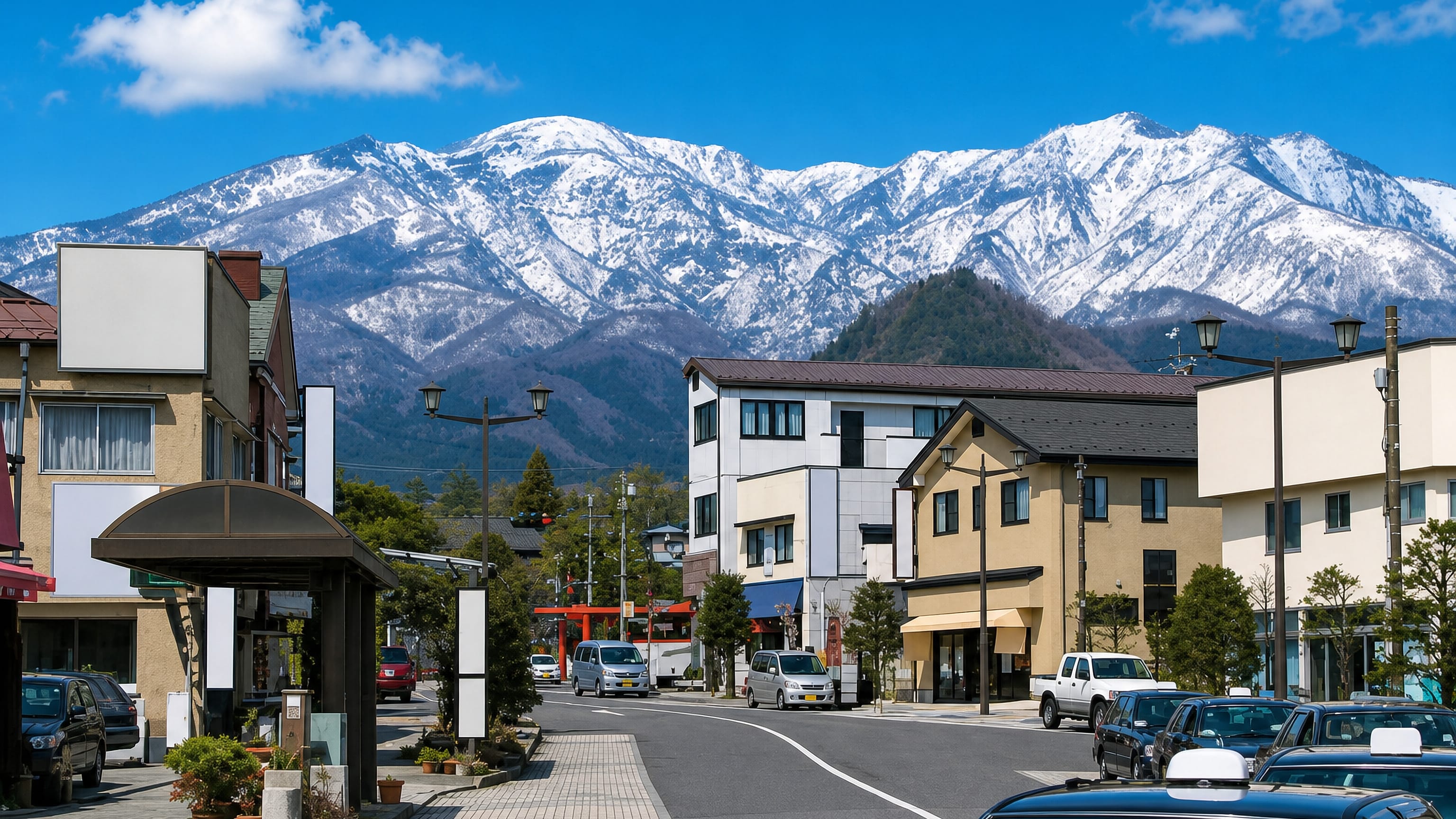 Main street in Nikko lined with shops and taxis, a red torii ahead and snow-capped peaks behind.
