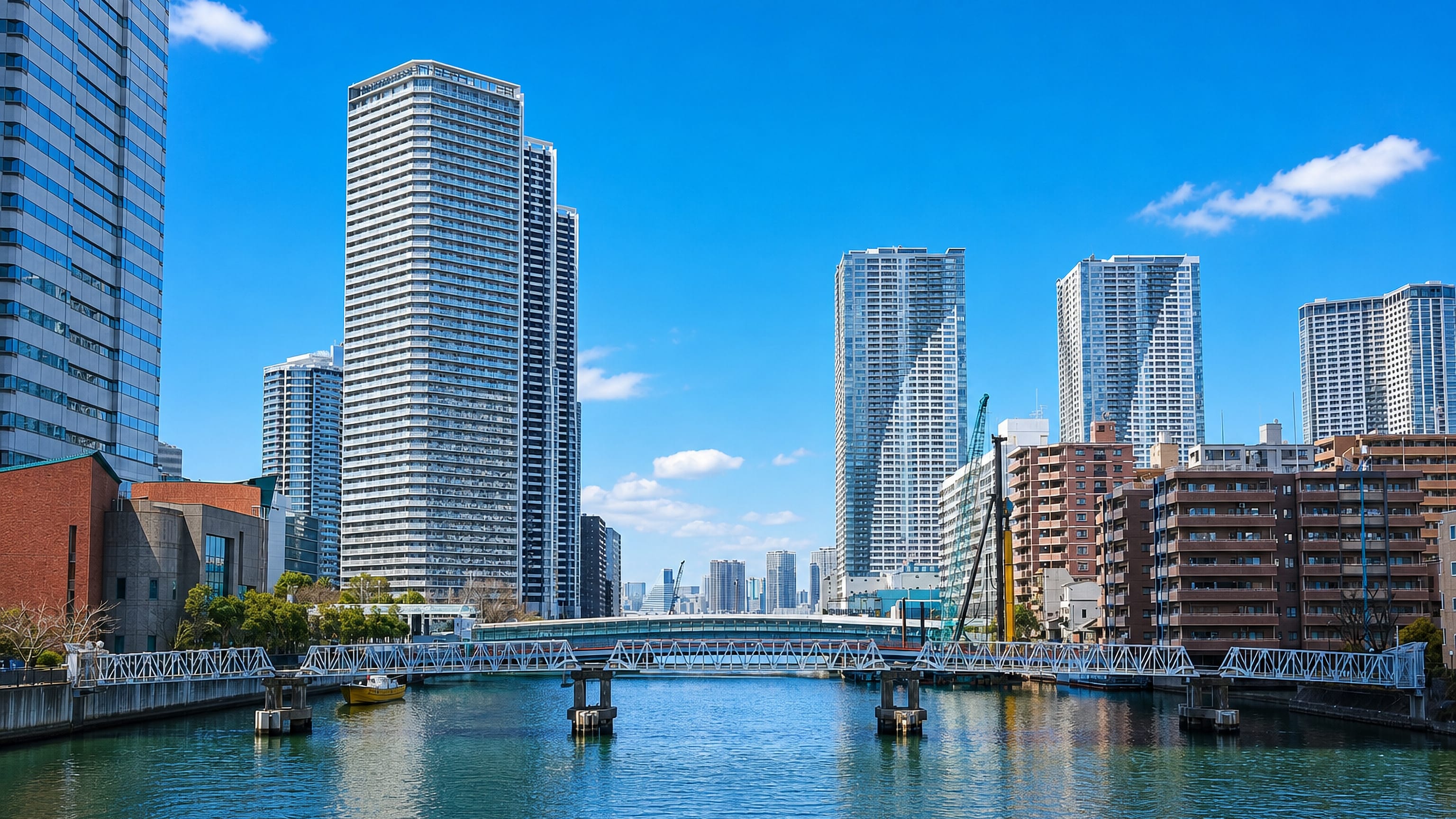 Canal-side high-rise towers and a low bridge in Kachidoki, Chuo ward, Tokyo, on a clear day.