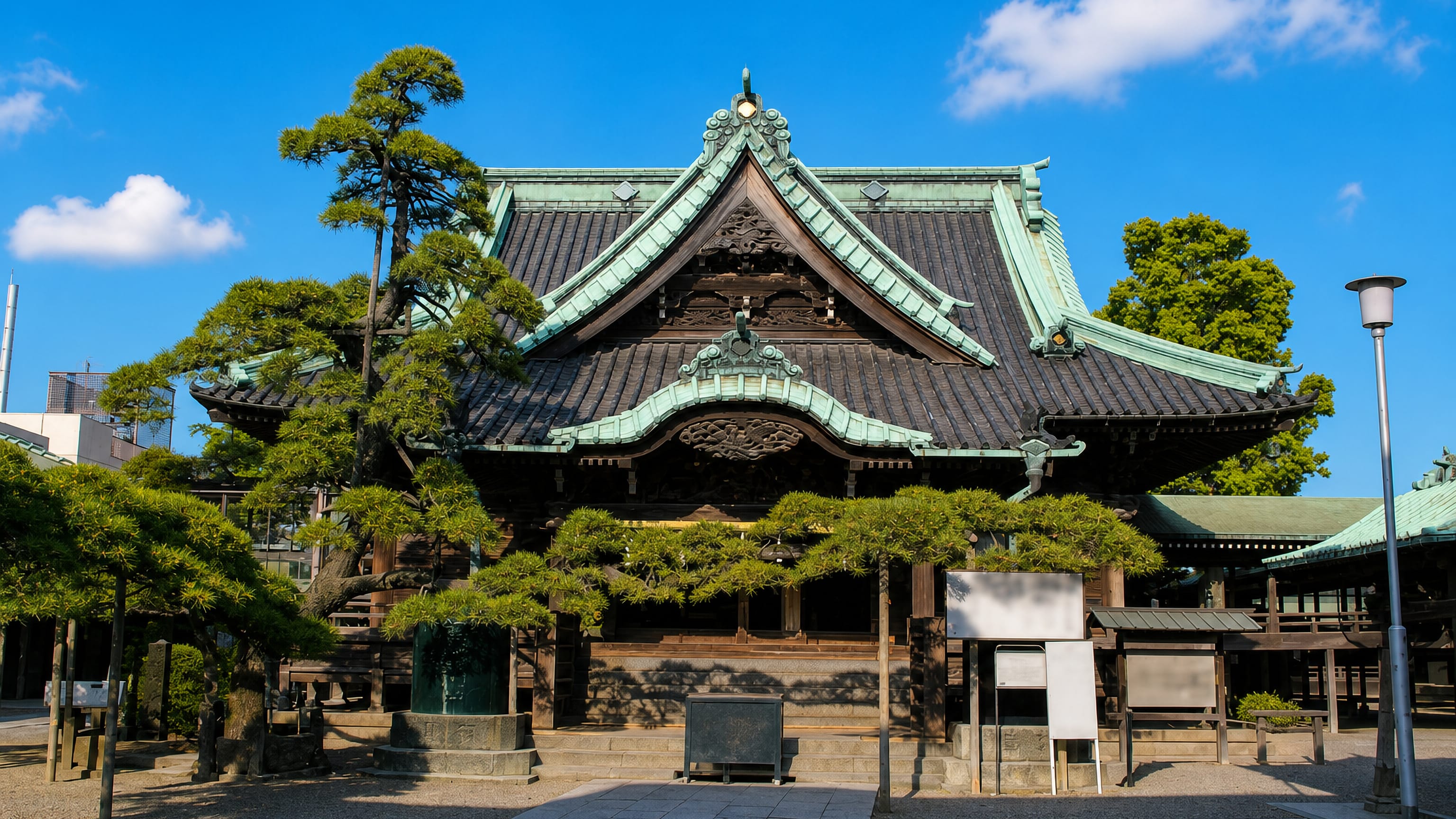 The carved wooden main hall of Shibamata Taishakuten temple with shaped pines in Katsushika, Tokyo.