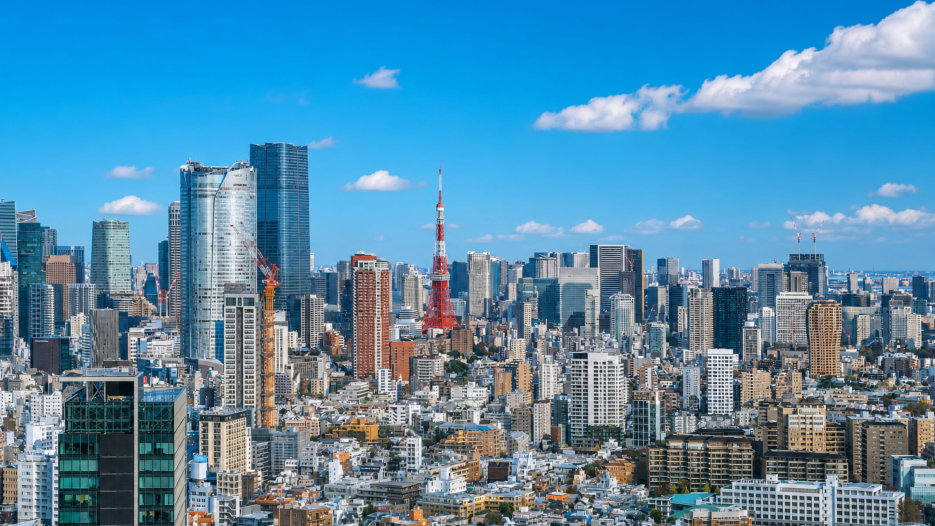 Minato City skyline in Tokyo with Tokyo Tower and the Azabudai Hills towers above dense low-rise blocks