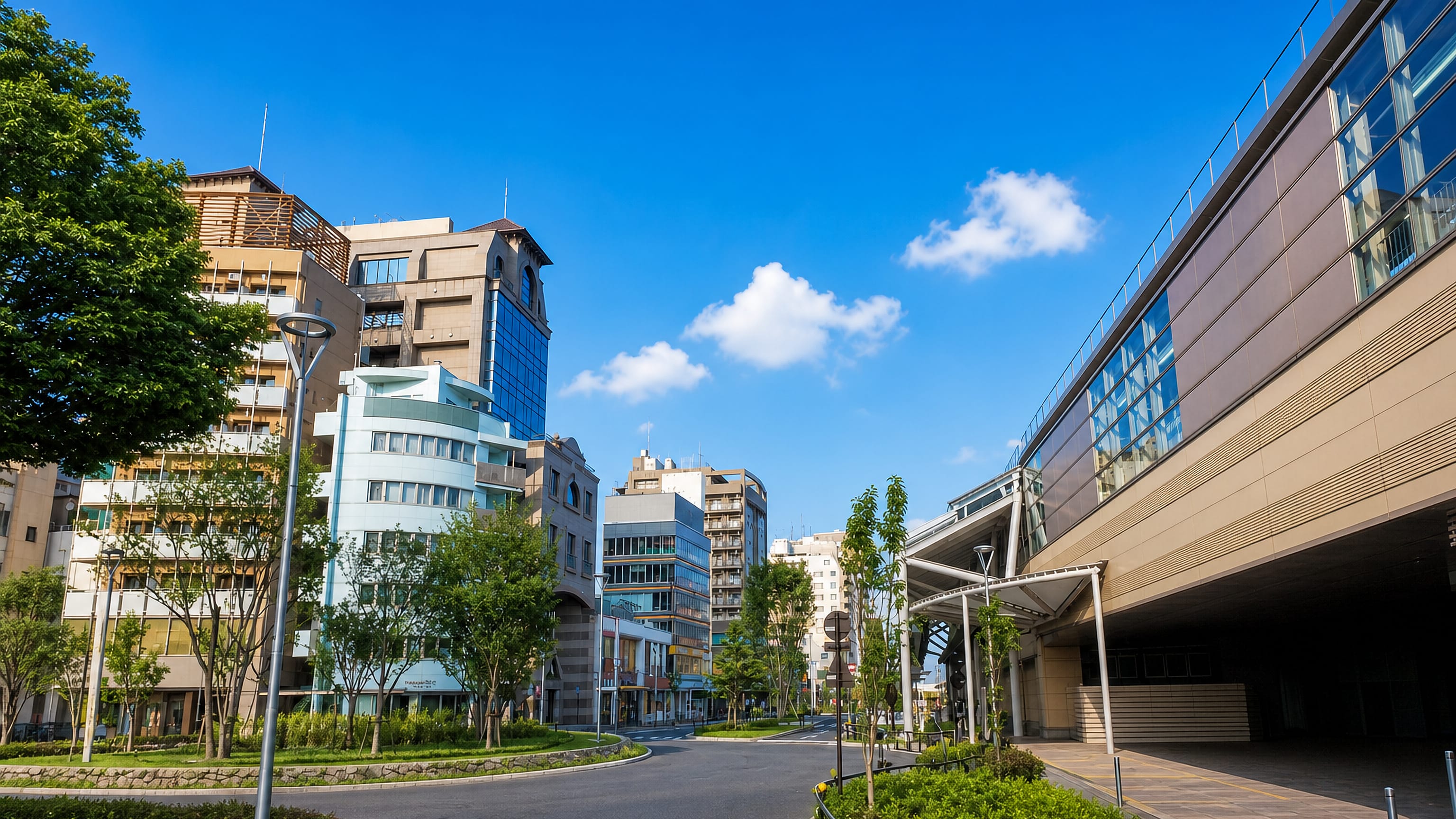 Station plaza and mid-rise shopfronts under a clear sky in Musashino, western Tokyo.