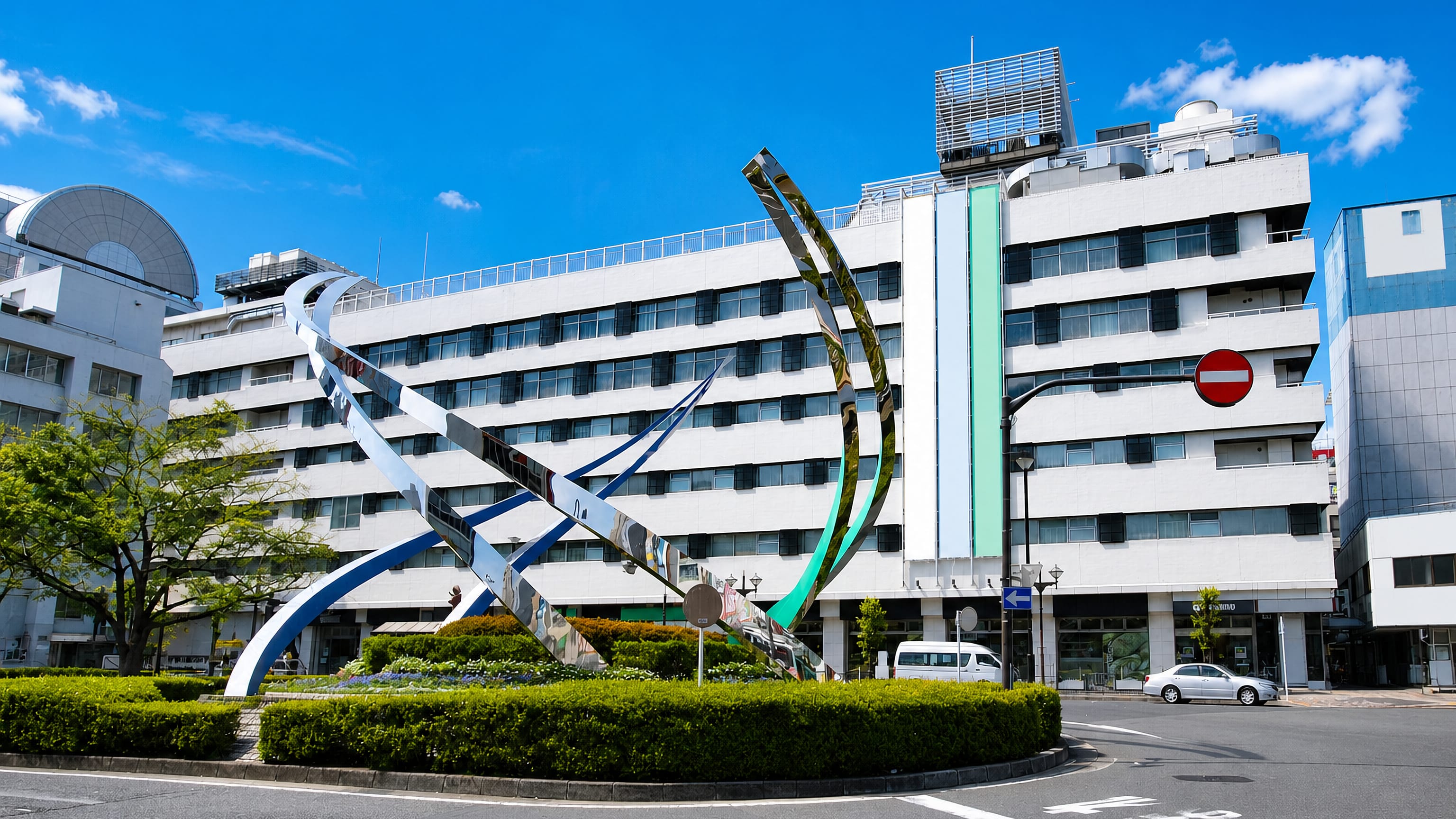 Abstract steel sculpture and mid-rise buildings at a street junction in Kamata, Ota, Tokyo.