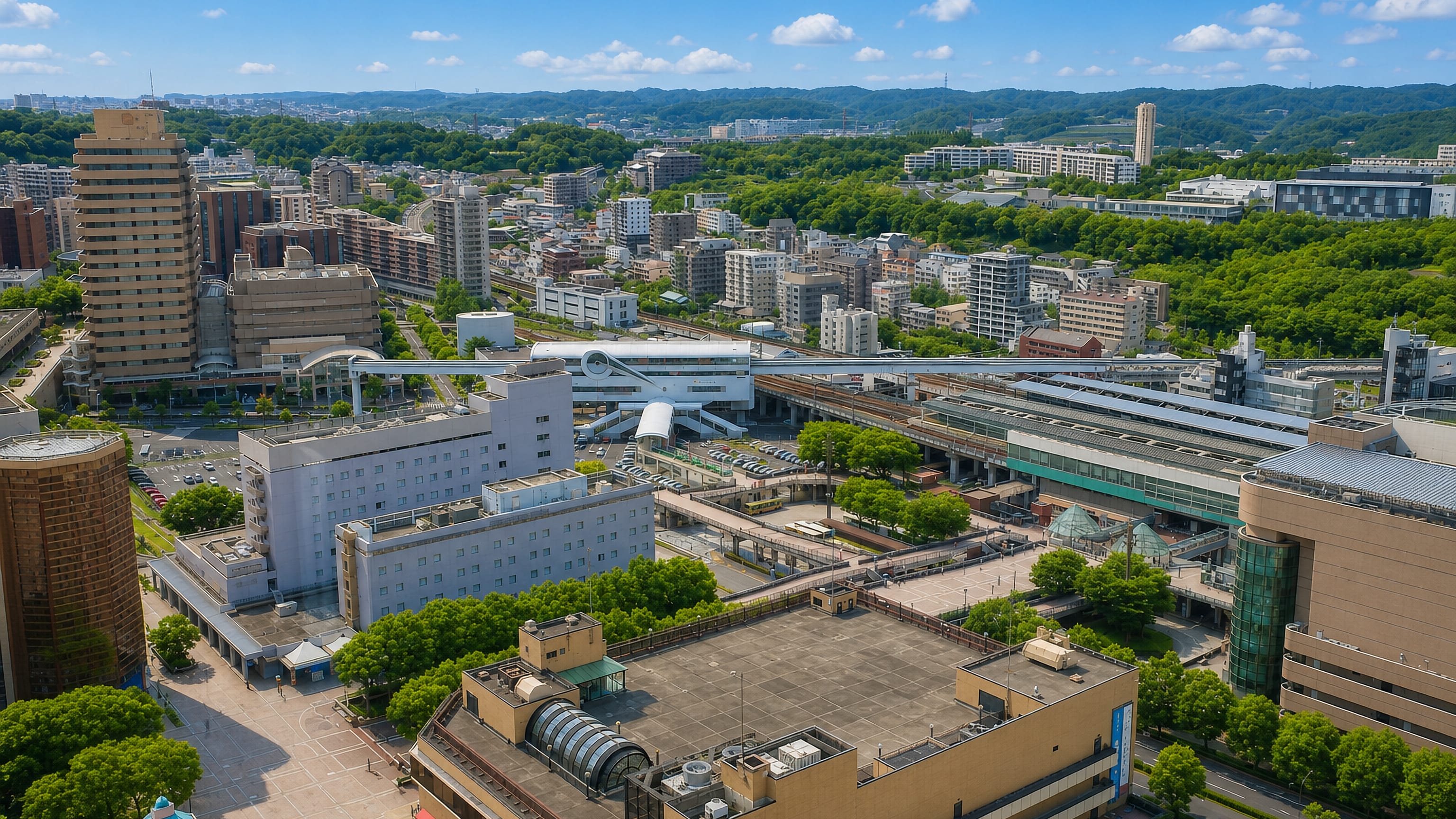 Pedestrian decks, elevated rail lines and mid-rise blocks against wooded hills in Tama, western Tokyo.