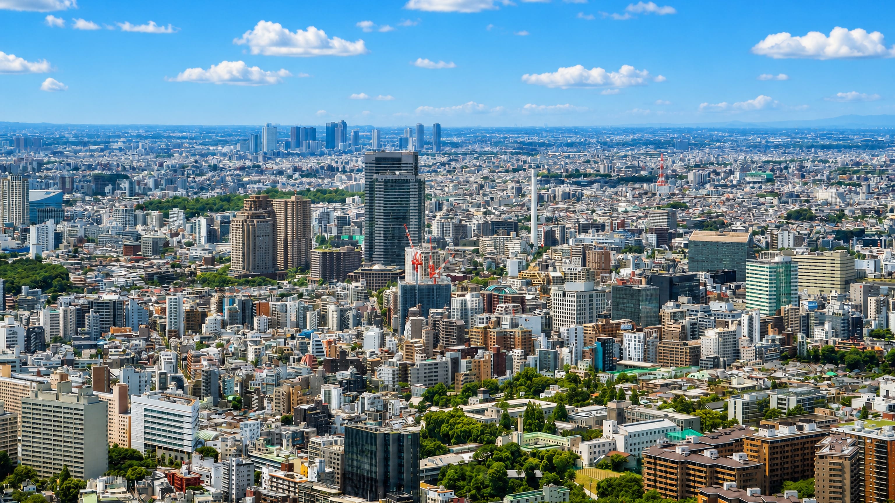 Aerial view over the dense cityscape of Ebisu, Tokyo, with the Shinjuku skyline on the horizon.