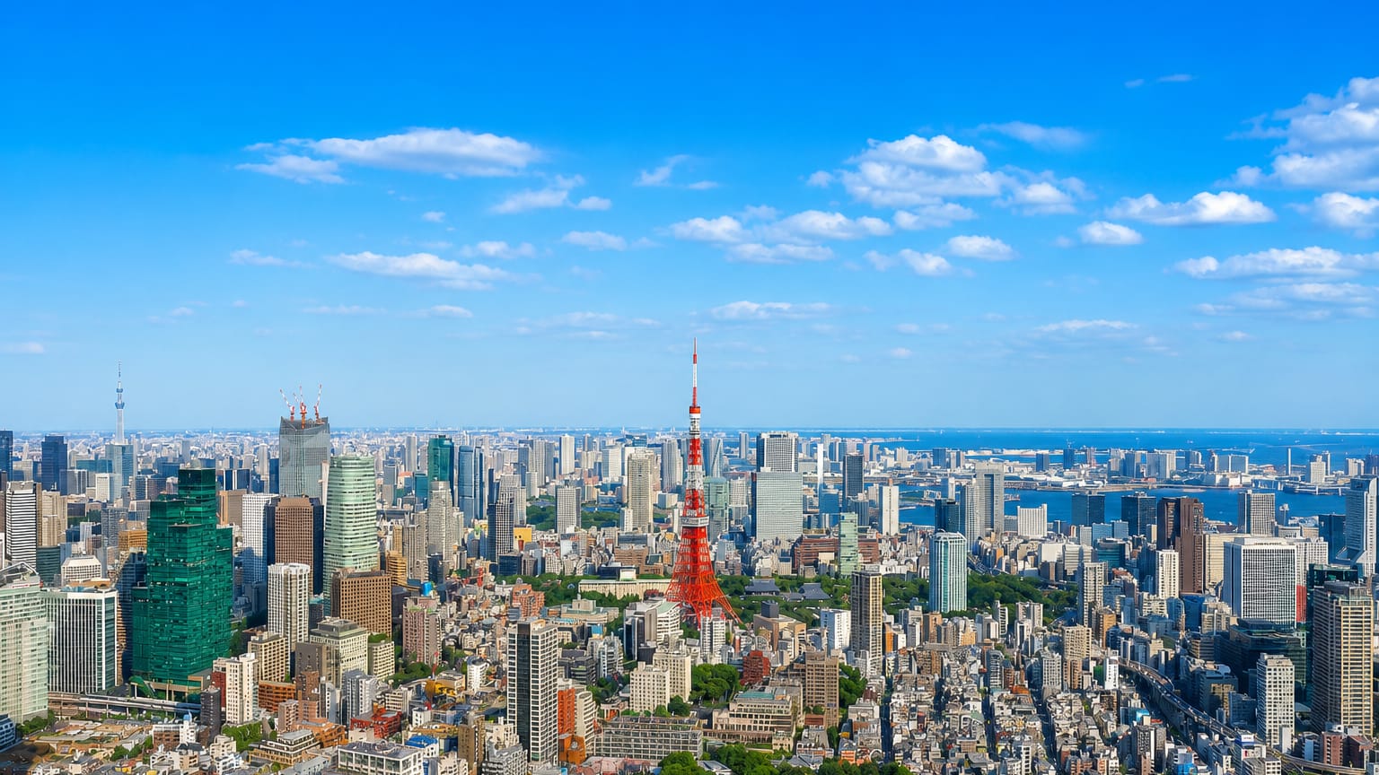 Tokyo skyline with the red-and-white Tokyo Tower and distant Tokyo Skytree above dense districts and the bay.