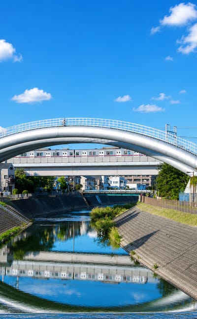 Arched footbridge and elevated railway over a channelled river in suburban Machida, Tokyo.