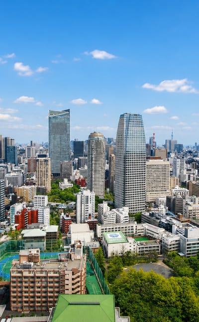 Minato ward skyline in Tokyo with the conical Izumi Garden Tower and surrounding high-rises under a blue sky