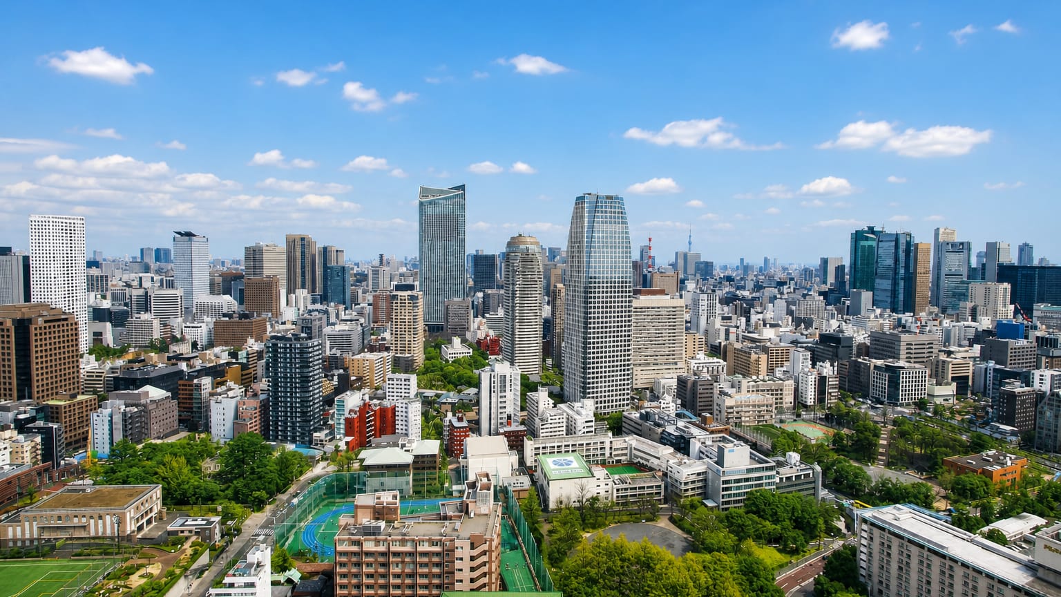 Minato ward skyline in Tokyo with the conical Izumi Garden Tower and surrounding high-rises under a blue sky