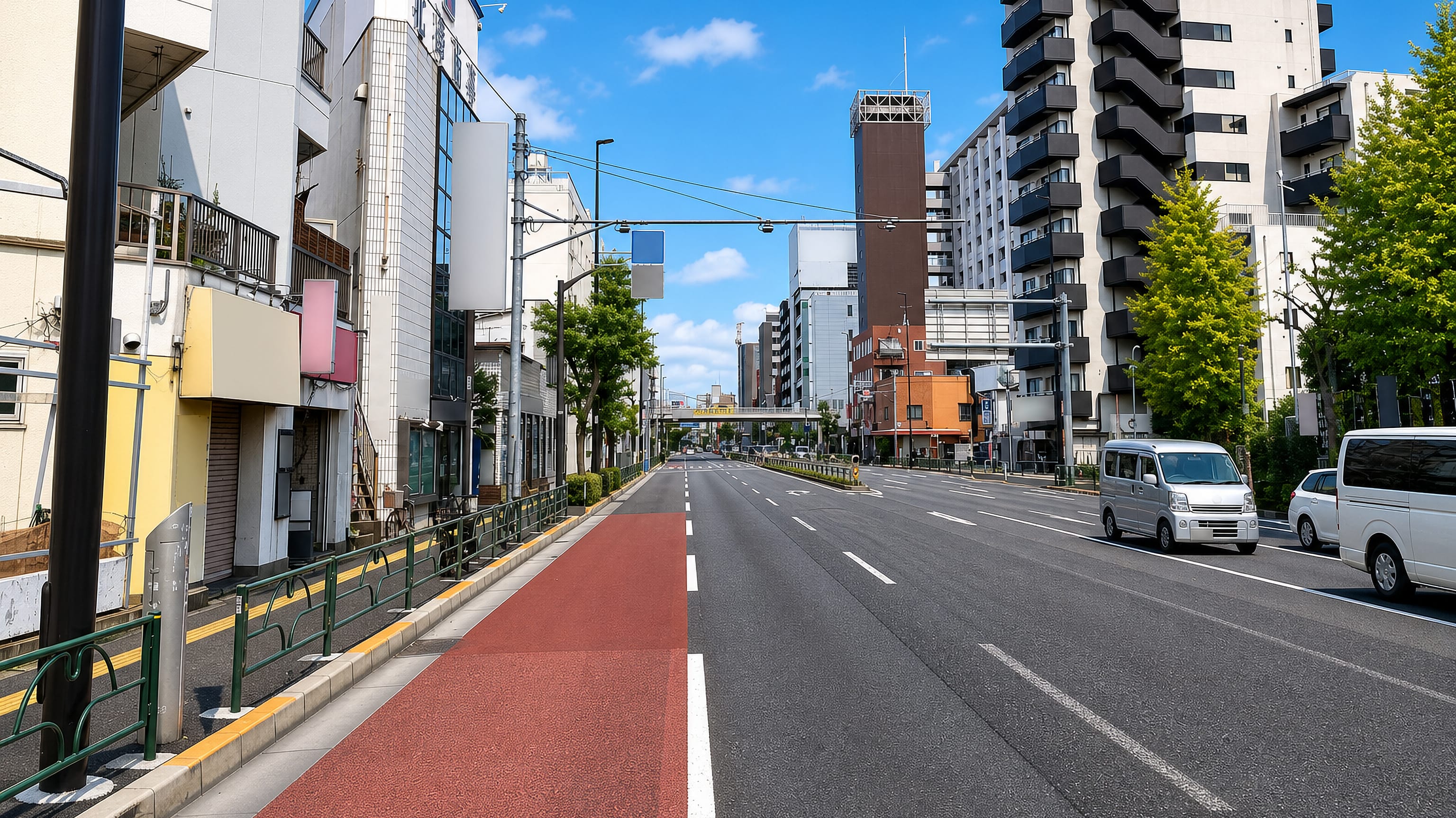 Wide arterial road with red cycle lane and apartment blocks in Nishiarai, Adachi, Tokyo.