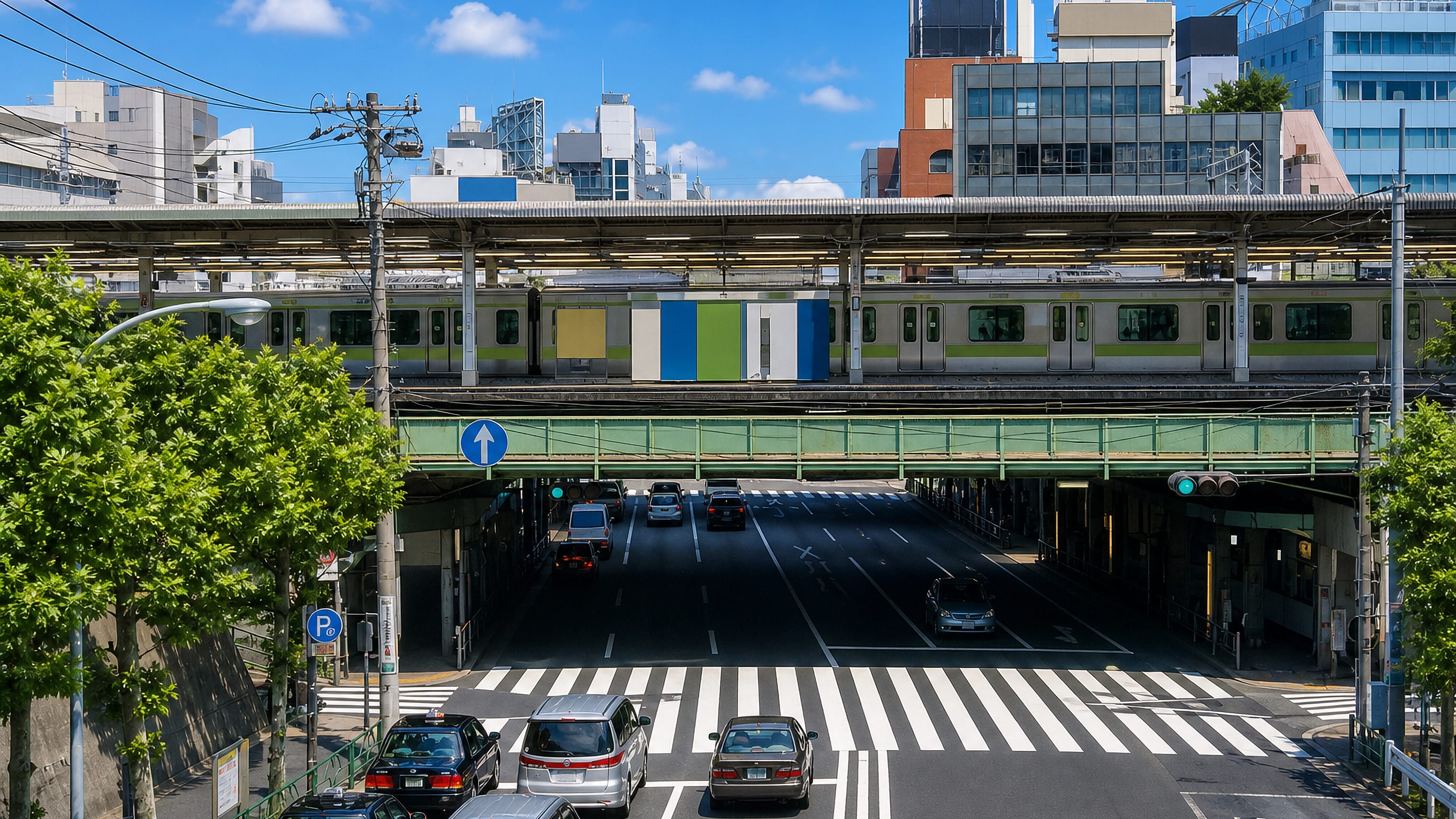 A commuter train crossing an elevated viaduct above a busy road at Nishinippori in northern Tokyo.