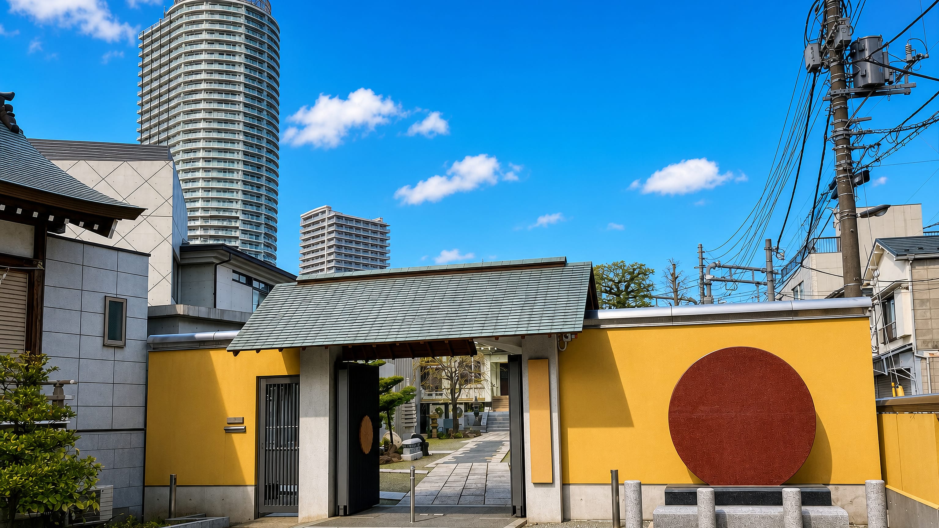 A yellow-walled temple gate on an Oshiage backstreet in Tokyo, with a round residential tower behind