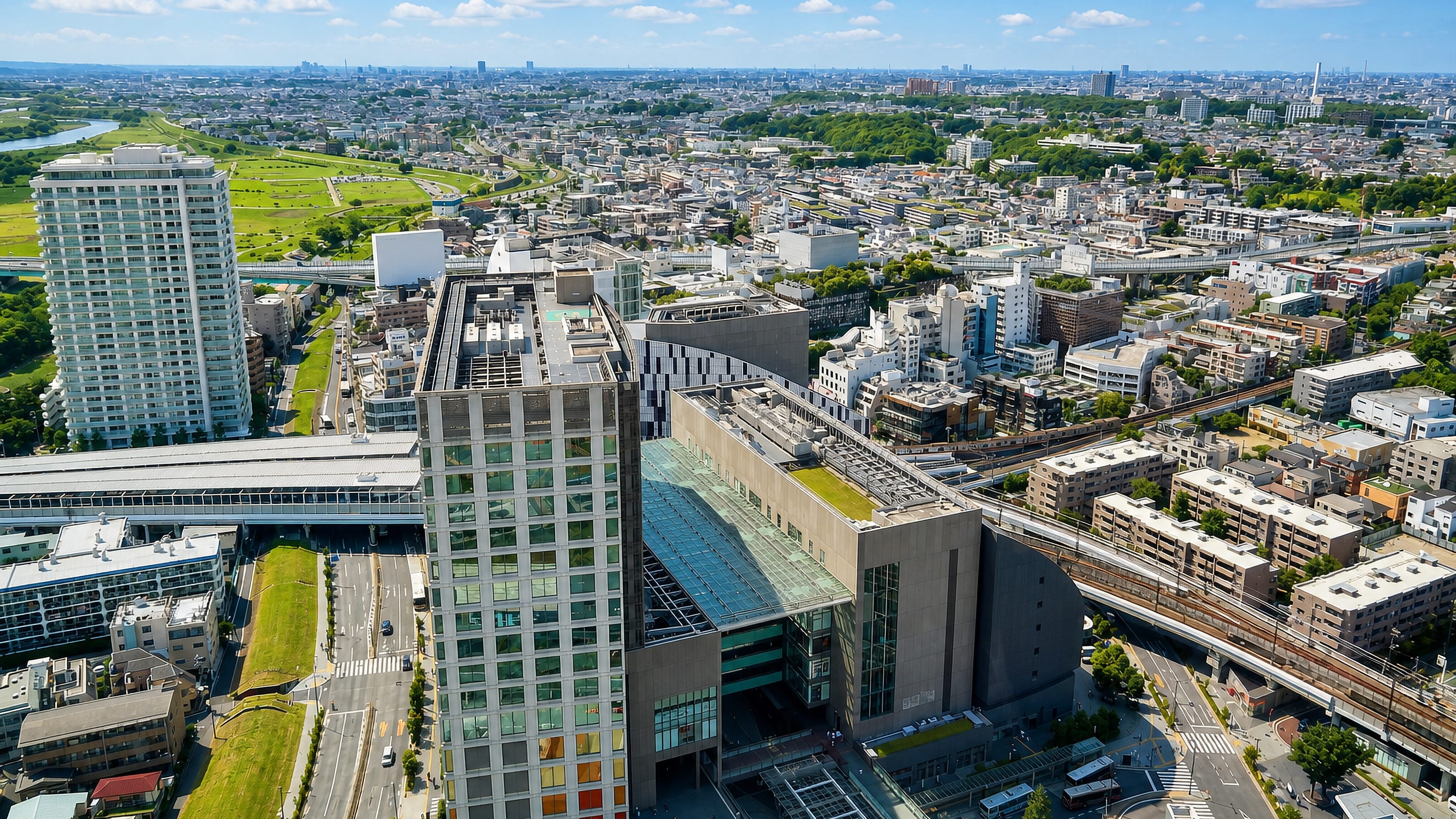 Aerial view of Setagaya, Tokyo, with a large station and retail complex, rail viaducts and the Tama River beyond.