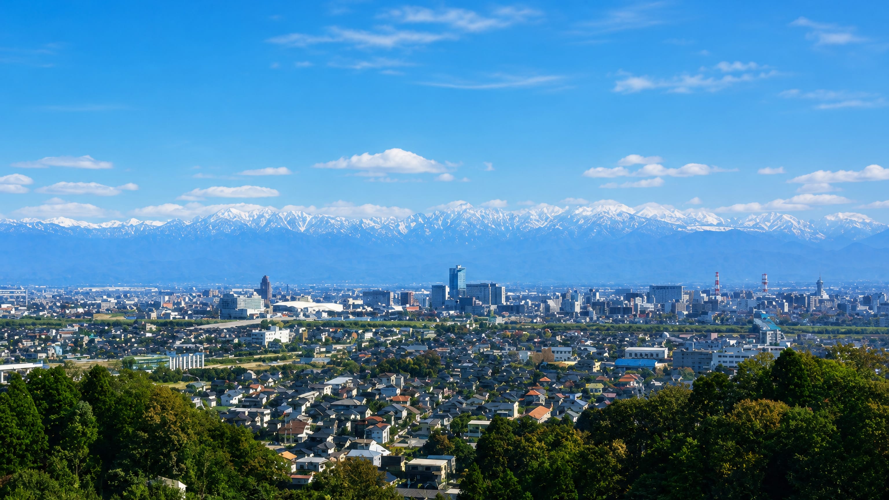 Toyama spreading across its plain below the snow-capped Tateyama mountain range on a clear day.