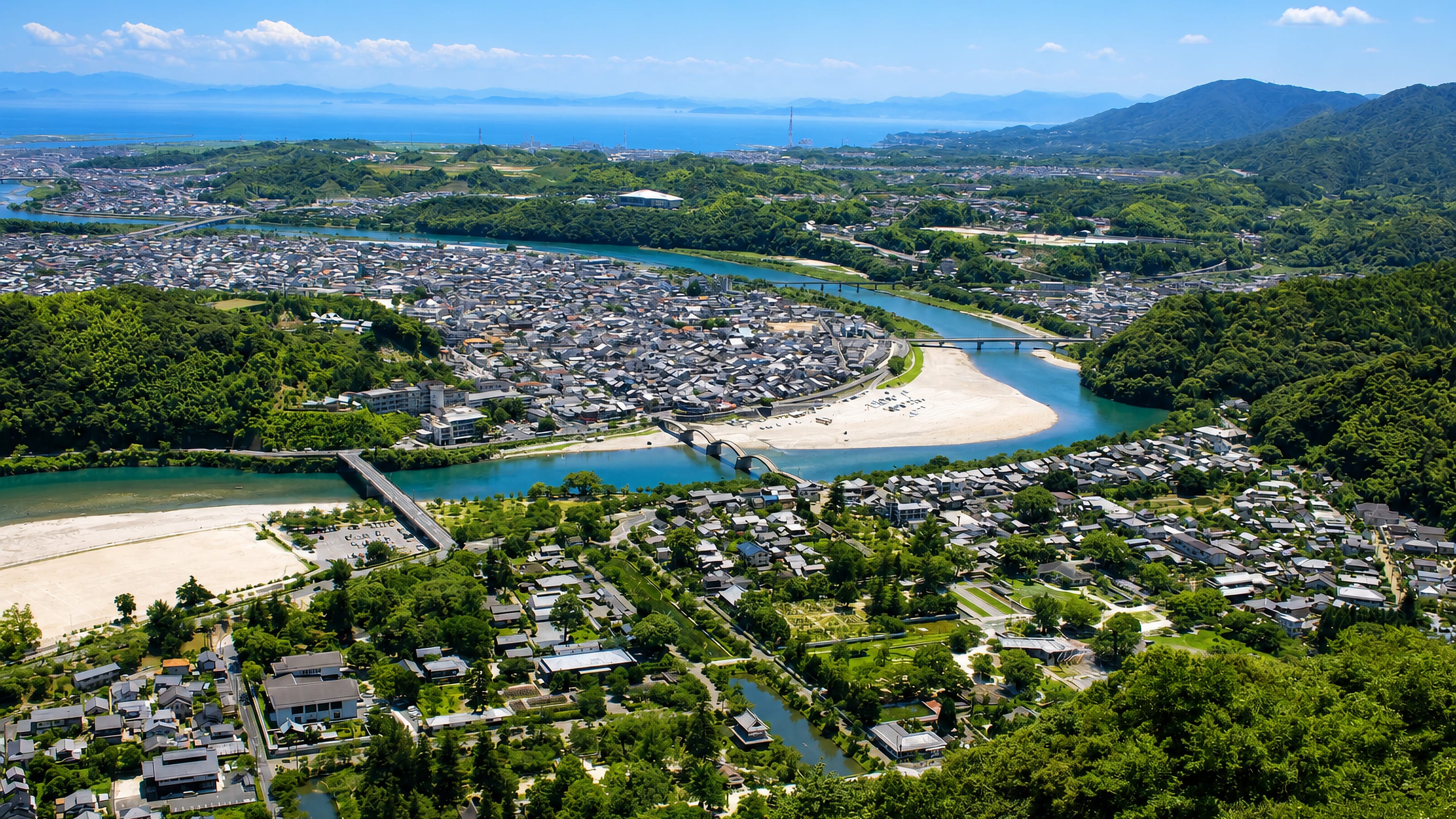 The Nishiki River curves past the arched Kintai Bridge and the rooftops of Iwakuni, Japan, toward the Seto Inland Sea.