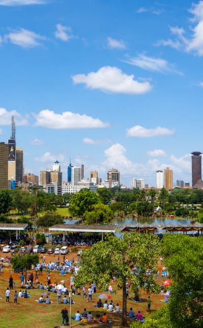 Nairobi skyline with the cylindrical Kenyatta International Convention Centre tower seen across a green park.