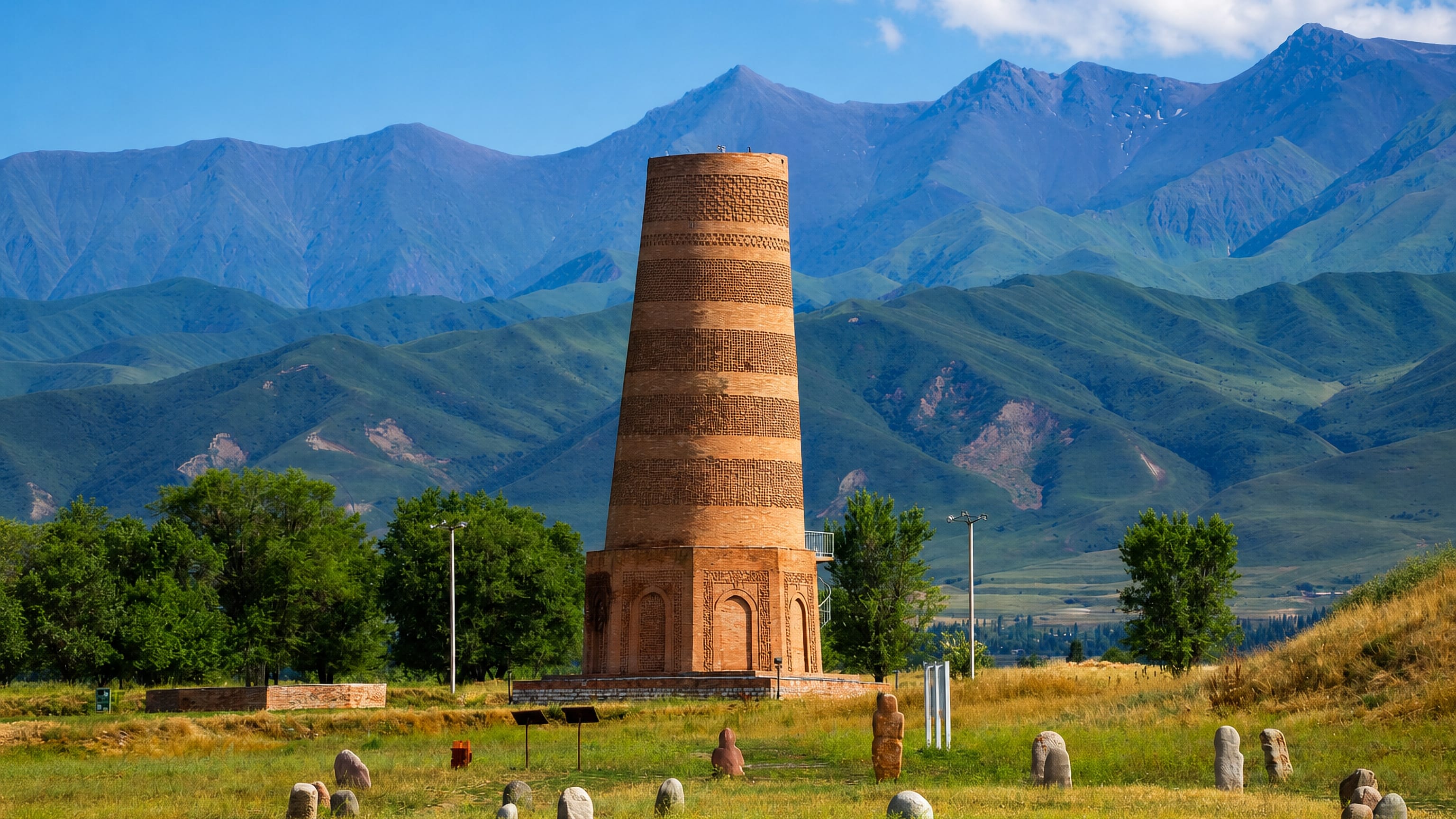 The brick Burana Tower and balbal stone figures near Tokmok, Kyrgyzstan, below the Kyrgyz Ala-Too range