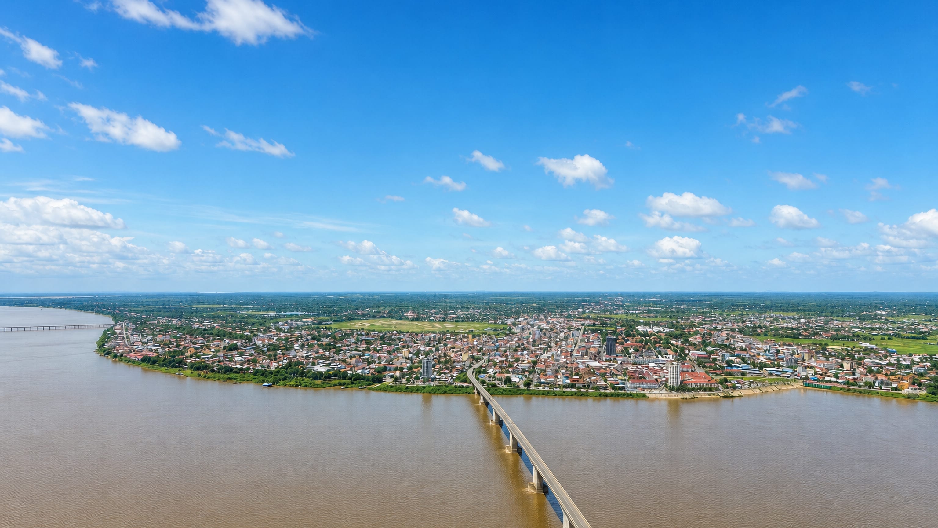 Aerial view of Kampong Cham on the Mekong River, its riverside town spread beside a long concrete bridge.